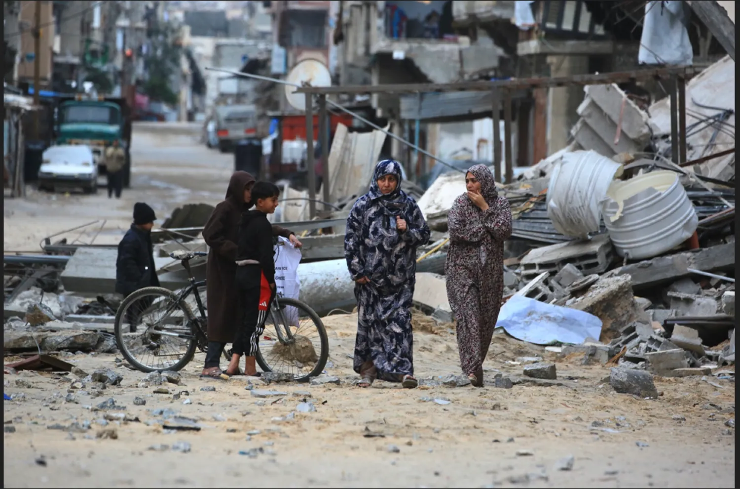 امرأة فلسطينية نازحة تسير بين الأنقاض والحطام في خان يونس جنوب قطاع غزة (أ.ف.ب)