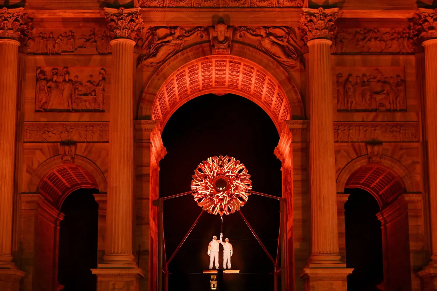 ألبرتو تومبا وديبورا كومبانيوني يحملان الشعلة الأولمبية تحت المرجل في ساحة «آركو ديلا باتشي» وسط ميلانو (إ.ب.أ).