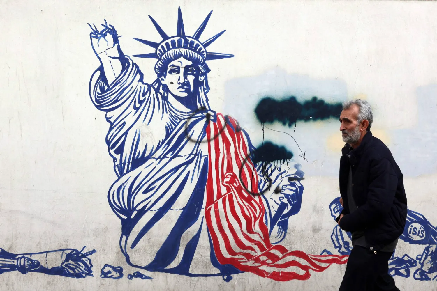 A man walks past a mural depicting the US Statue of Liberty with the torch-bearing arm broken, painted on the outer walls of the former US embassy, in Tehran on February 6, 2026. (AFP)