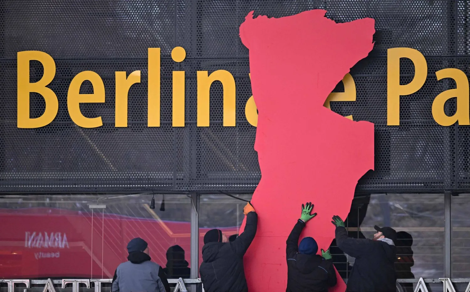 عمال يركّبون دبّ مهرجان برلين السينمائي الدولي على واجهة قصر برلين المقر الرئيسي للمهرجان استعداداً لانطلاق فعالياته (أ.ف.ب)