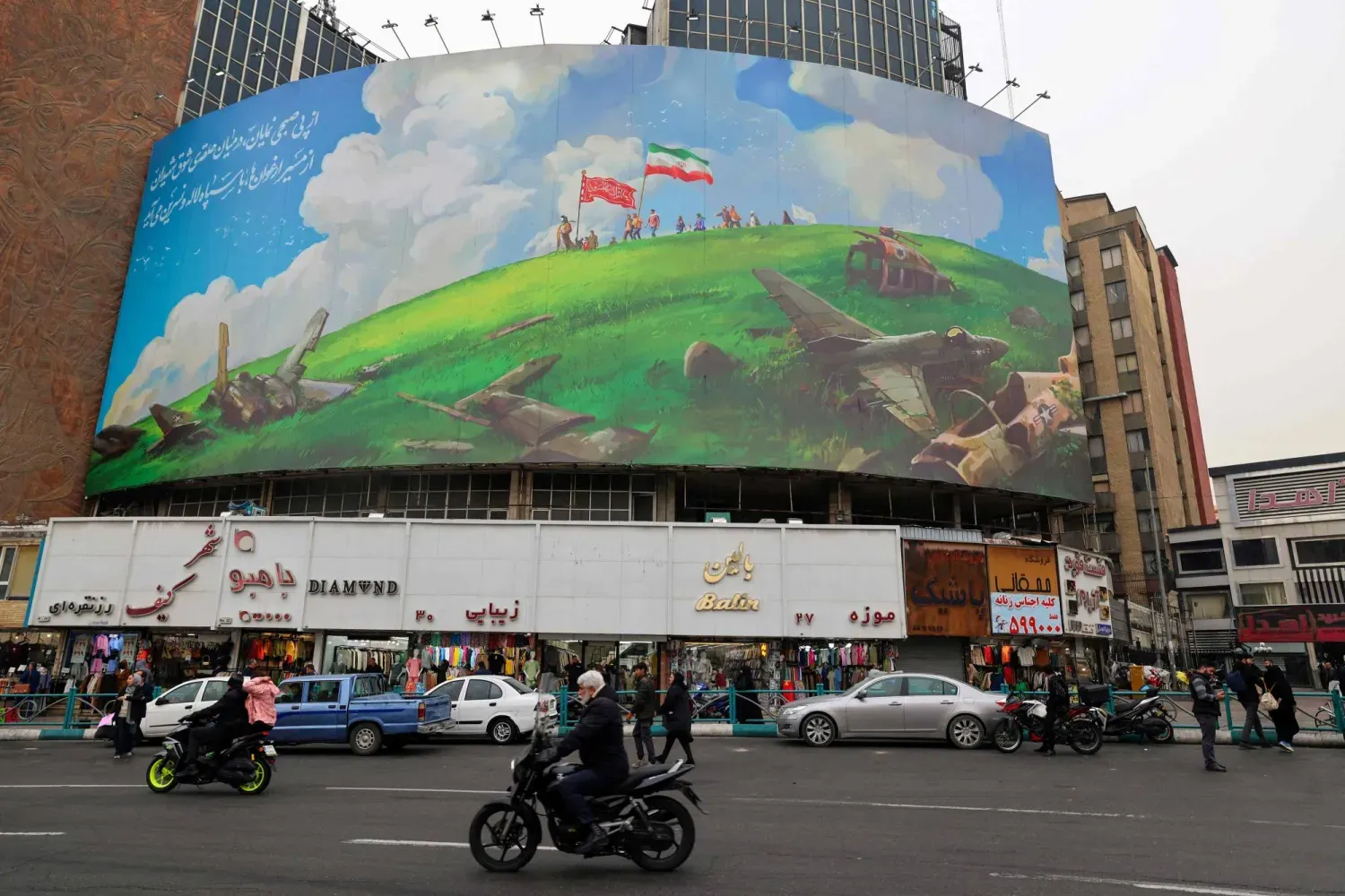 Tahran’daki bir meydanda bulunan binanın üzerinde yer alan ABD karşıtı afişin önünden geçen İranlılar