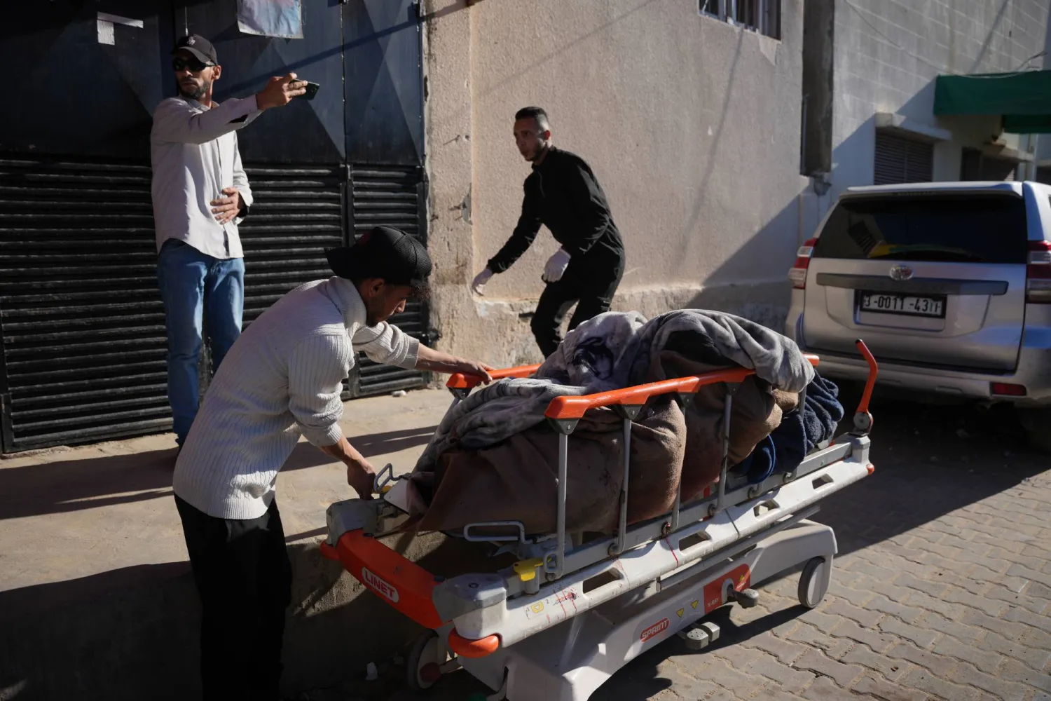 رجل فلسطيني يدفع نقالة تحمل جثتَي شخصين في مستشفى «الأقصى» قُتلا في غارة جوية شنها الجيش الإسرائيلي على مخيم في دير البلح وسط قطاع غزة يوم 4 فبراير 2026 (أ.ب)