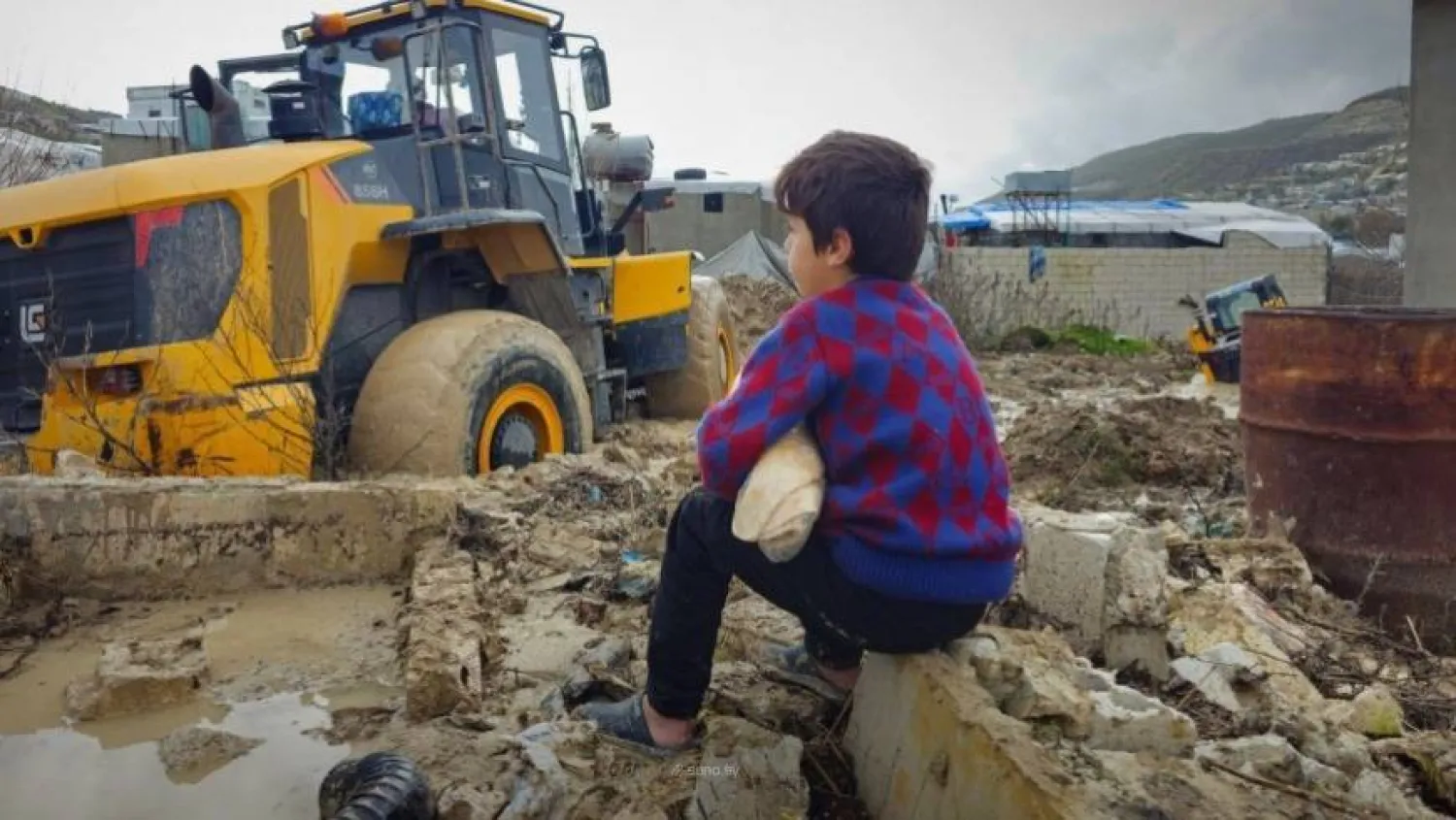 A child watches as civil defense teams open flooded roads in Idlib. (SANA) 