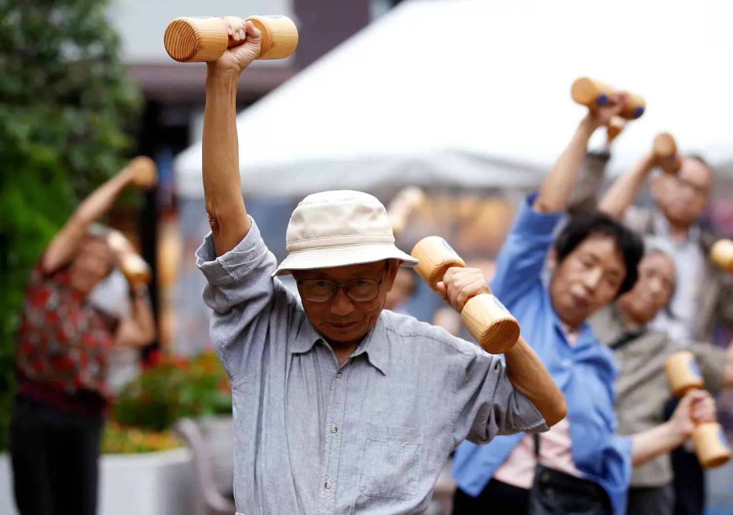كبار السن ومتوسطو العمر يمارسون تمارين رياضية باستخدام أثقال خشبية خلال فعالية للتوعية الصحية في معبد بحي سوغامو بطوكيو (أرشيفية-رويترز)