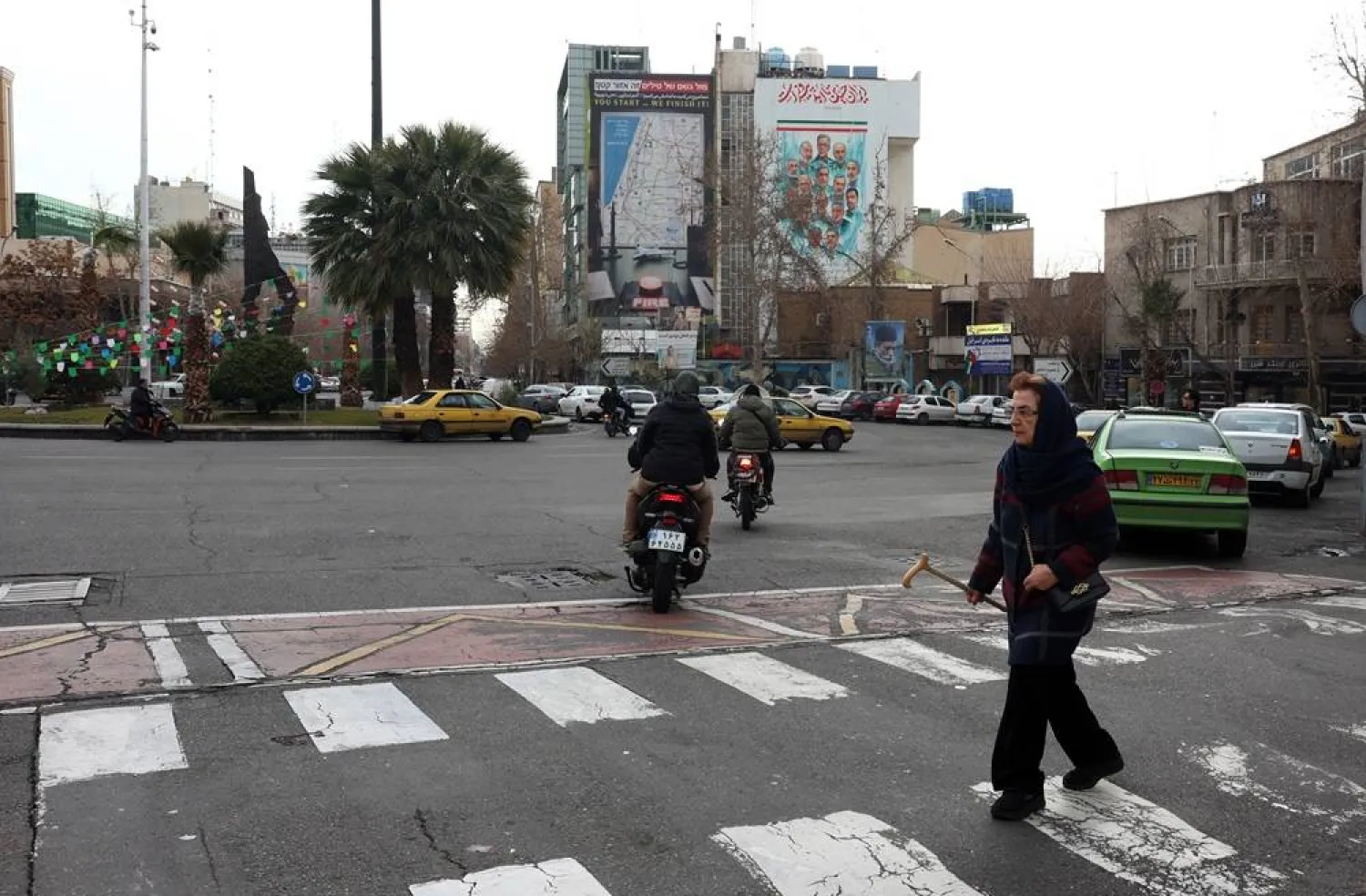 Iranians cross a road near an anti-US and anti-Israeli billboard reading "You start... we finish it" in Palestine Square in Tehran, Iran, 09 February 2026, amid heightened regional tensions. (EPA)