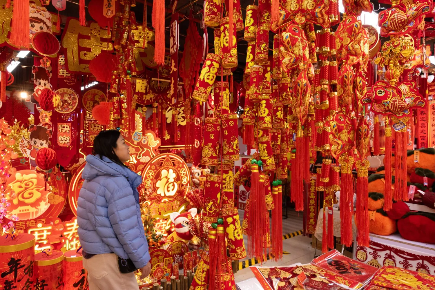 سيدة تشاهد زينات العام الجديد في إحدى الأسواق الشعبية بالعاصمة الصينية بكين (إ.ب.أ)