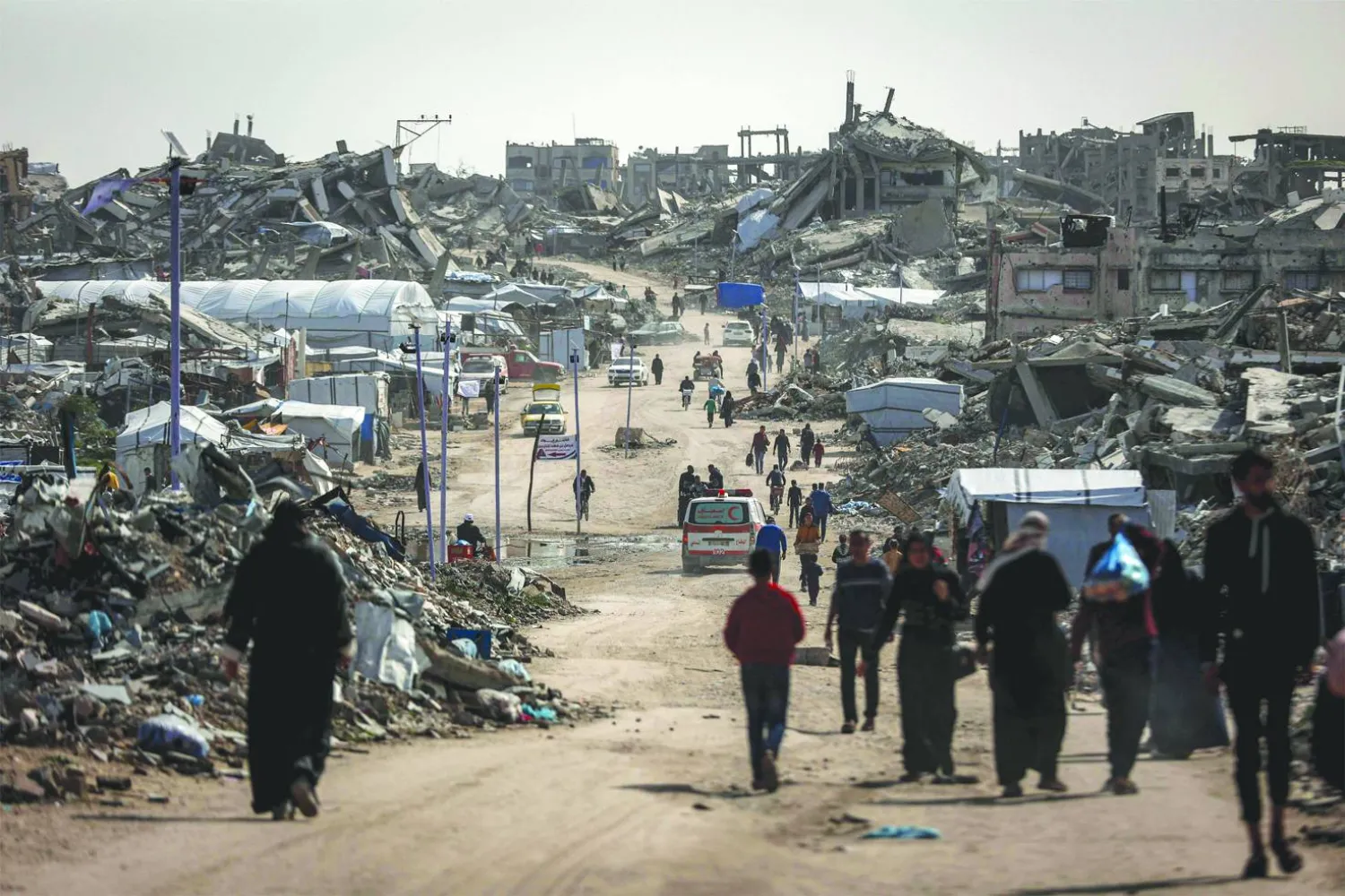 فلسطينيون يمشون وسط المباني المنهارة في مخيم جباليا للاجئين بشمال غزة (أ.ف.ب)