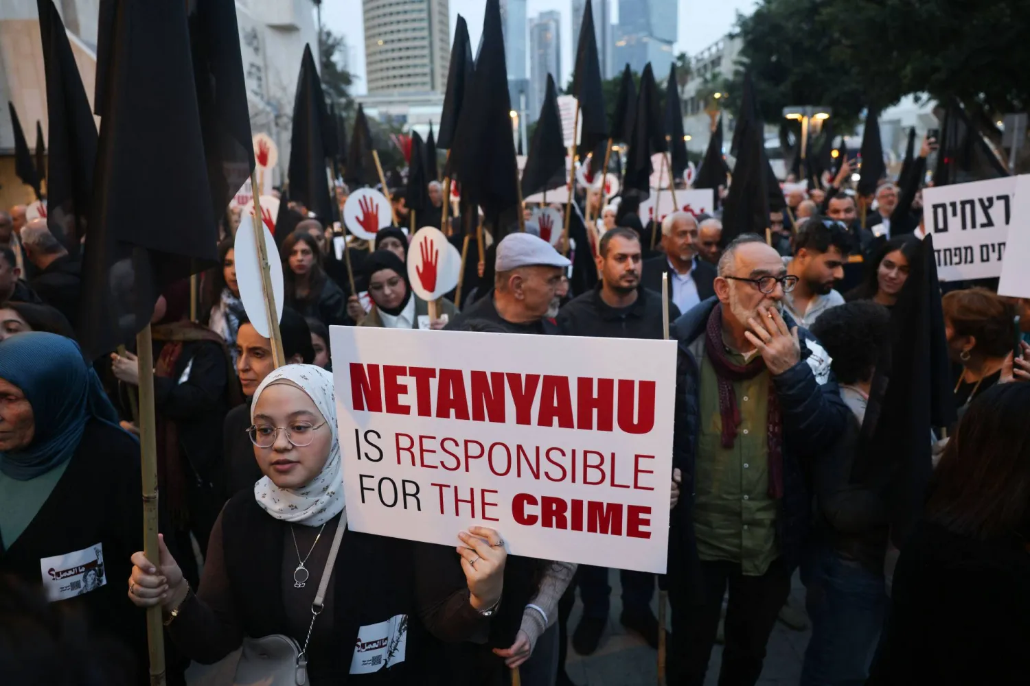 محتجون عرب في إسرائيل يحملون لافتات تحمّل حكومة نتنياهو المسؤولية عن تفشي الجرائم ضدهم خلال مظاهرة في تل أبيب (أ.ف.ب)