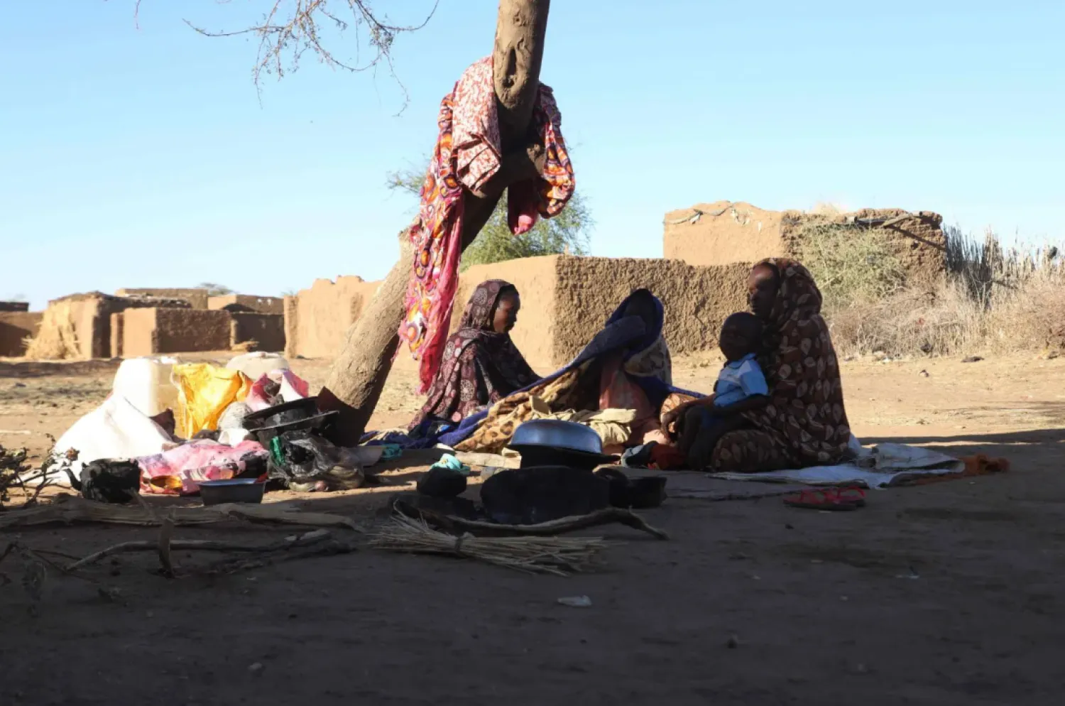 Sudanese displaced people who left El Fasher after its fall, sit in the shade in Tawila at the Rwanda camp reception point on December 17, 2025. (Photo by AFP)