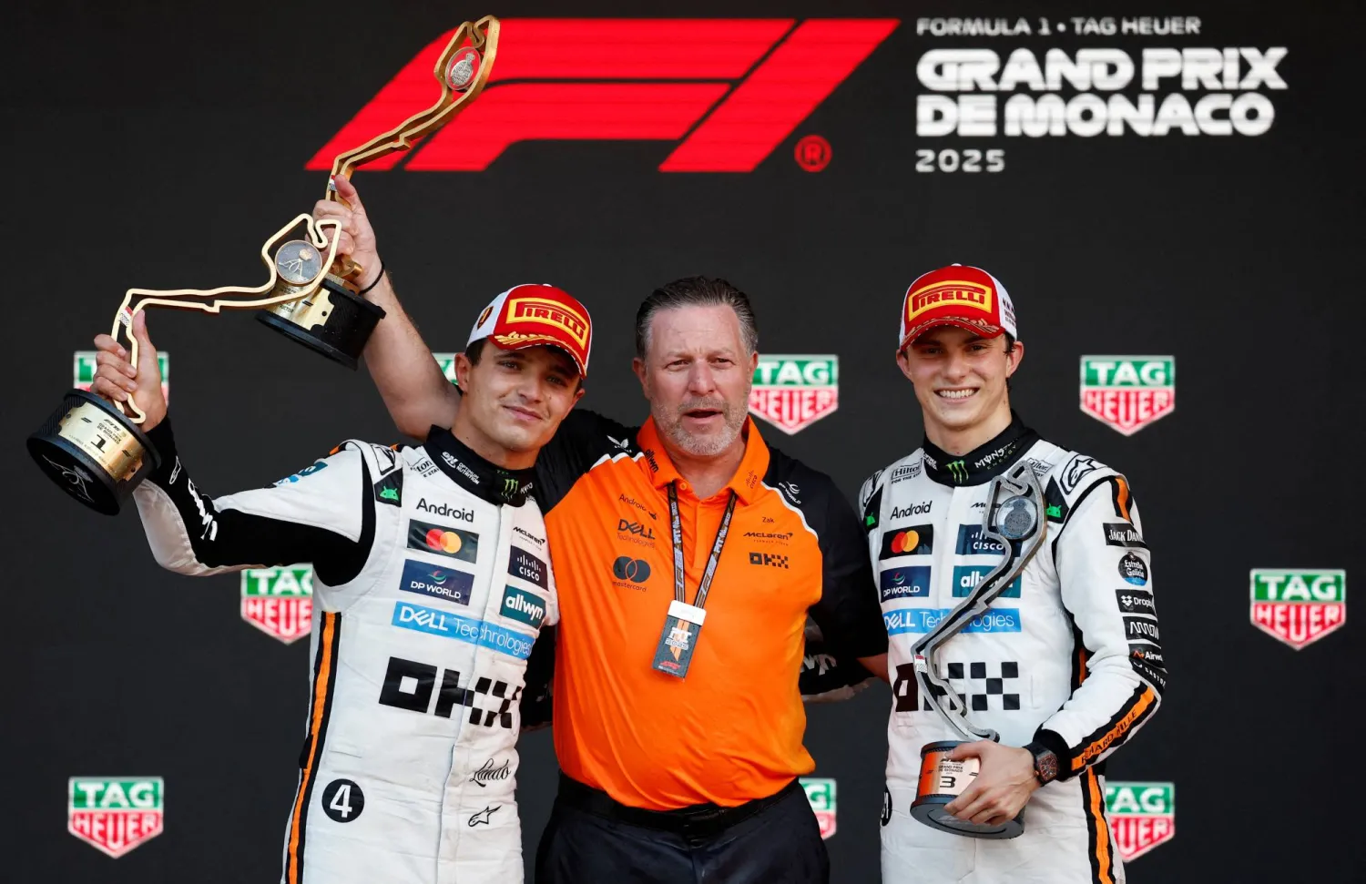 May 25, 2025 McLaren's Lando Norris celebrates with a trophy on the podium after winning the Monaco Grand Prix alongside third placed McLaren's Oscar Piastri and McLaren chief executive Zak Brown. (Reuters)