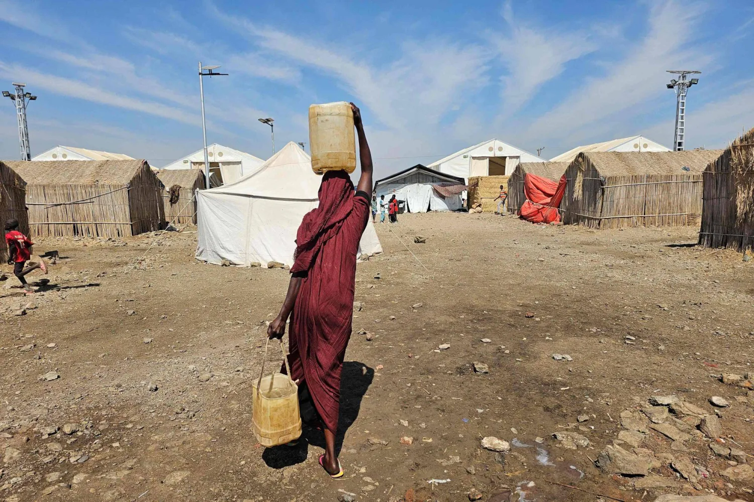 A displaced Sudanese woman carries plastic water containers at the Abu al-Naga displacement camp in the in Gedaref State, some 420km east of the capital Khartoum on February 6, 2026. (AFP)