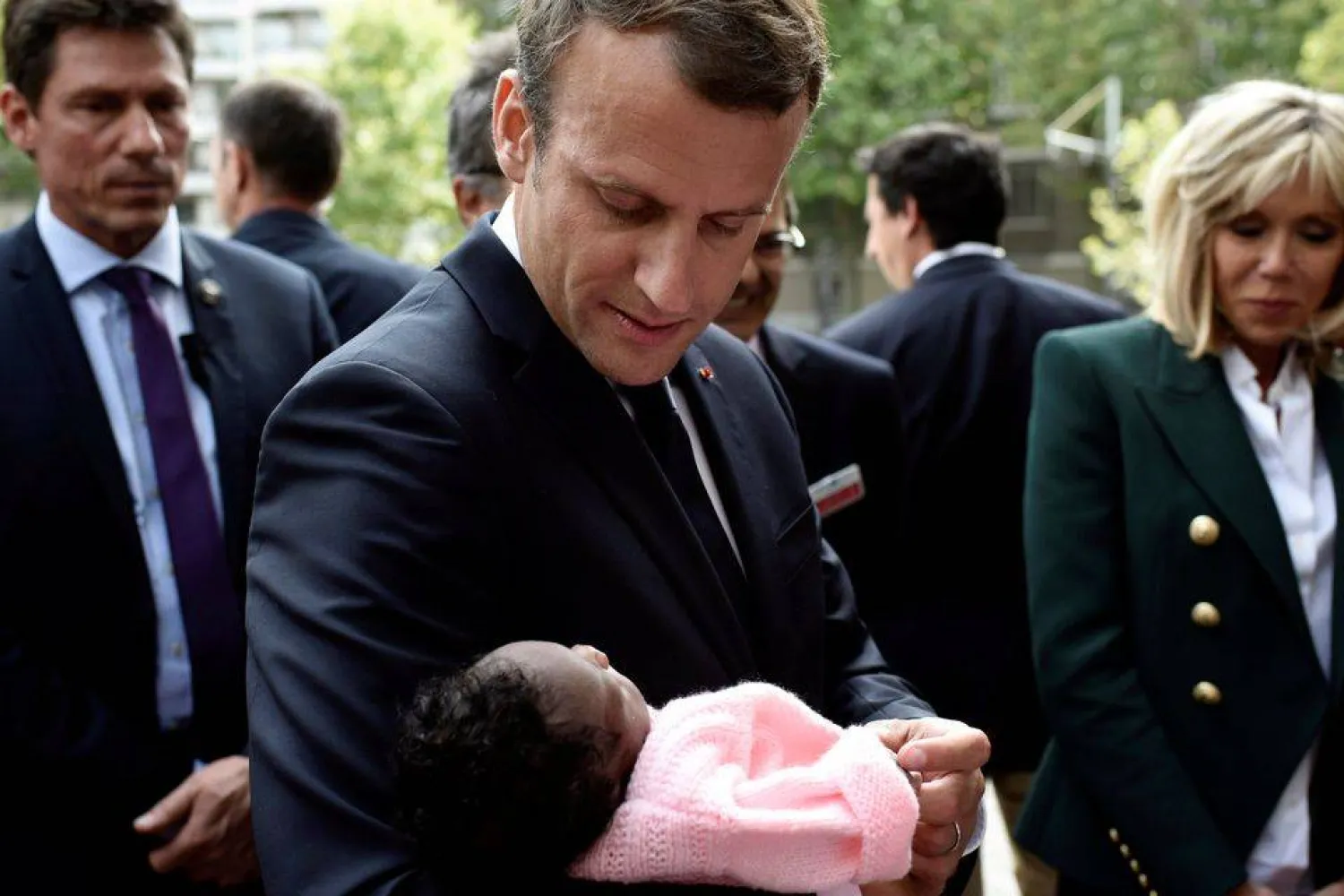 الرئيس الفرنسي إيمانويل ماكرون برفقة زوجته بريجيت يحمل رضيعة خلال زيارته لمستشفى روبرت ديبري للأطفال في باريس (رويترز)