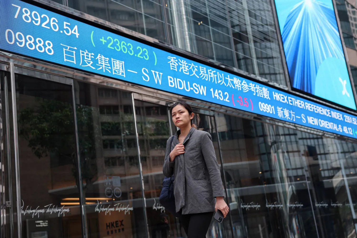 سيدة تمر أمام مقر البورصة في جزيرة هونغ كونغ الصينية (رويترز)