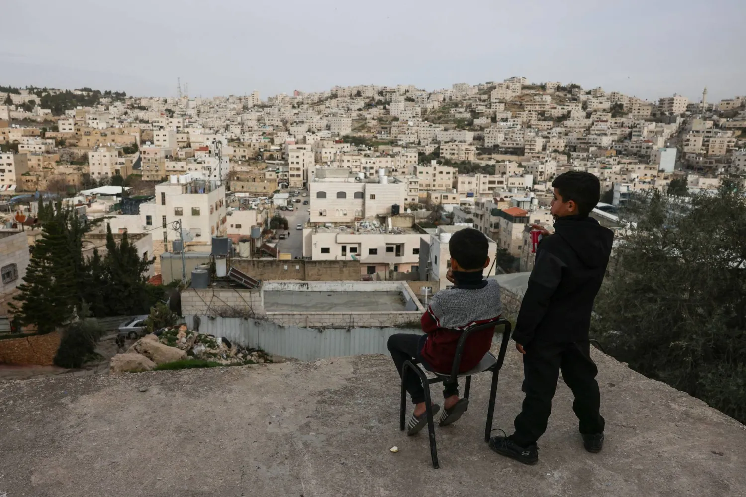 Palestinian boys look out over the Israeli-occupied West Bank city of Hebron from a rooftop on February 9, 2026. (AFP)
