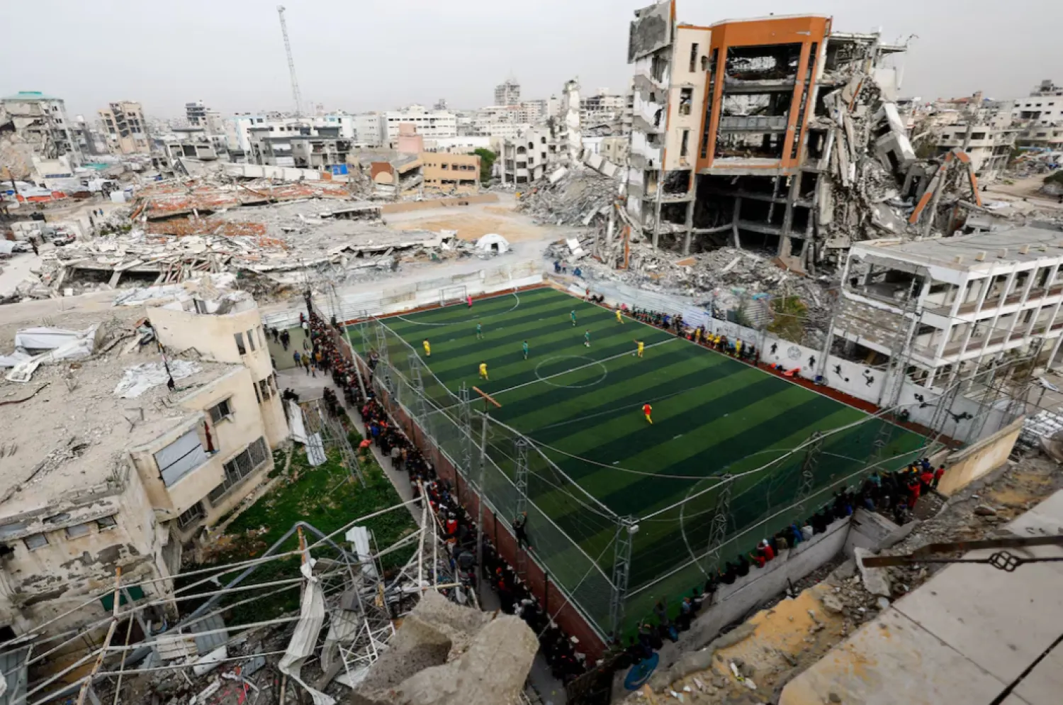 Palestinians play soccer on a pitch, near buildings destroyed during the two-year Israeli offensive, in Gaza City. REUTERS/Mahmoud Issa 