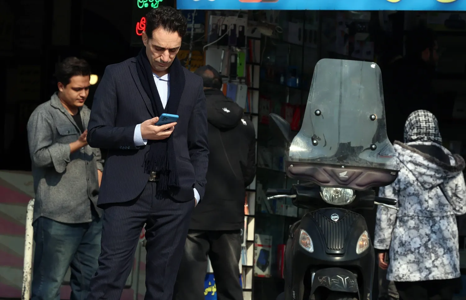 رجل إيراني يتفقد هاتفه في أحد شوارع طهران فيما تشهد البلاد انقطاعاً شاملاً للإنترنت 27 يناير (إ.ب.أ)