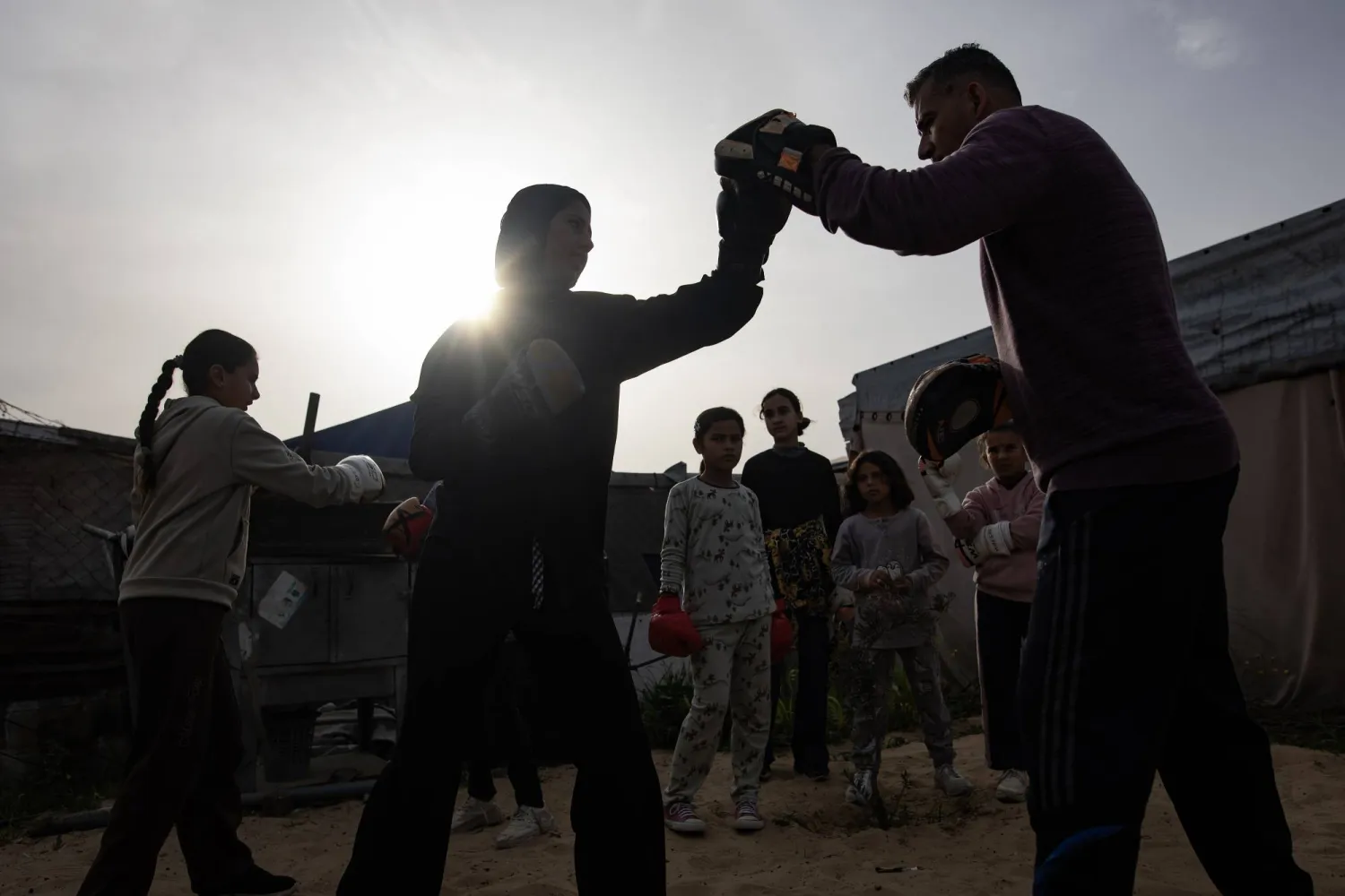 مدرب الملاكمة أسامة أيوب (يمين) يقوم بتدريب فتيات صغيرات داخل خيمة في منطقة المواصي بخان يونس جنوب قطاع غزة (إ.ب.أ)