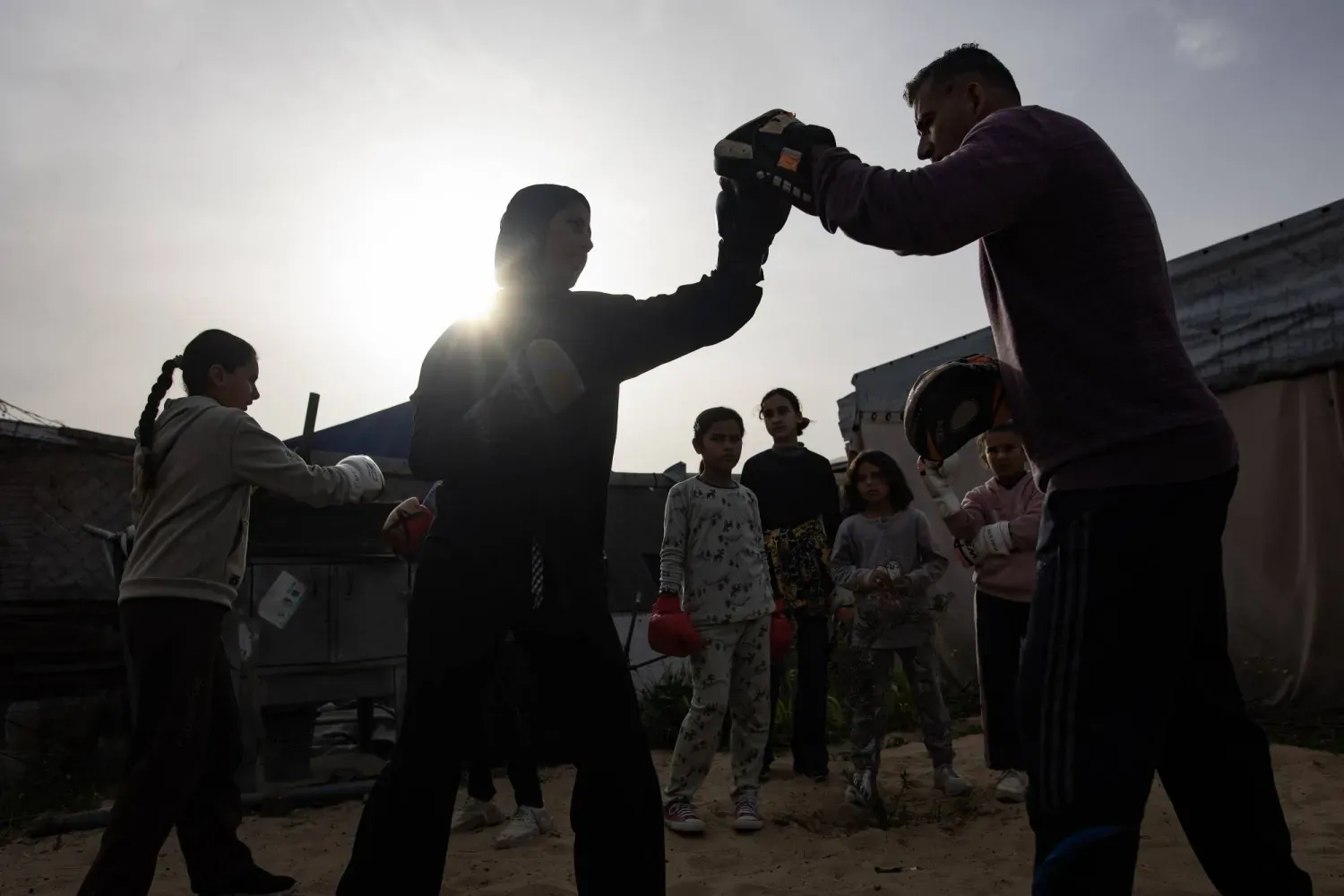 Boks antrenörü Usame Eyub (sağda), Gazze Şeridi'nin güneyindeki Han Yunus'un el-Mevasi bölgesinde bir çadırda genç kızları eğitiyor (EPA)