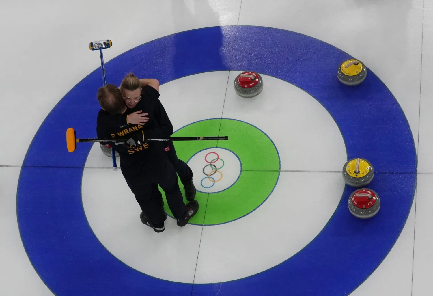 الشقيقان السويديان راسموس وإيزابيلا ورانا يحتفلان بالفوز بالزوجي المختلط للكيرلينج (رويترز)