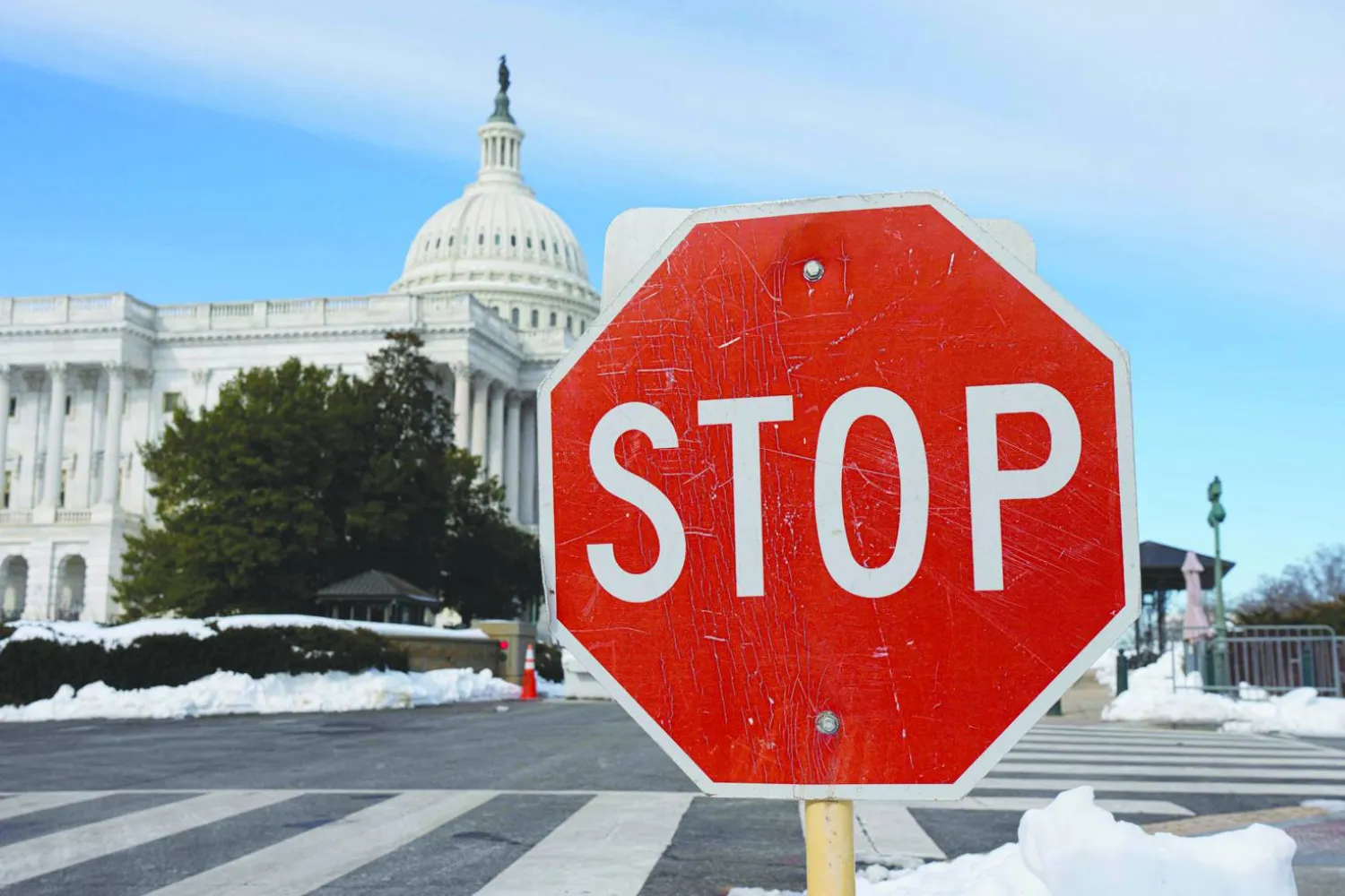 لافتة «توقف» وسط بقع من الثلج أمام مبنى الكابيتول الأميركي في واشنطن... 31 يناير 2026 (أ.ف.ب)