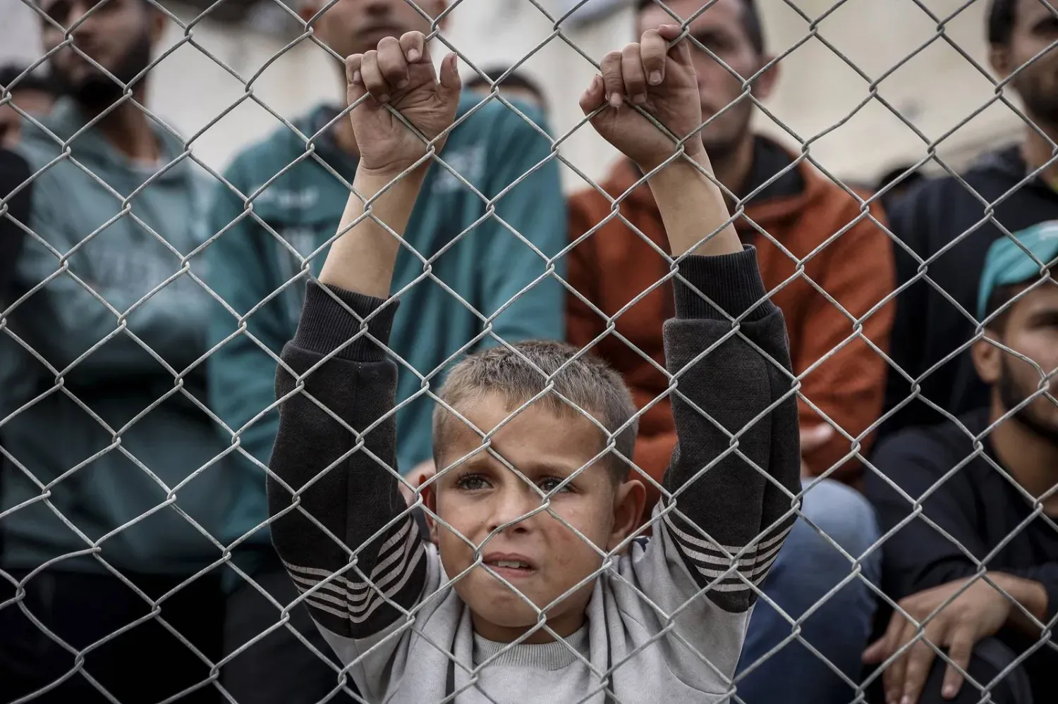 Gazze şehrinde yıkılmış binaların enkazı arasında tel örgülere tutunmuş Filistinli bir çocuk (AFP)