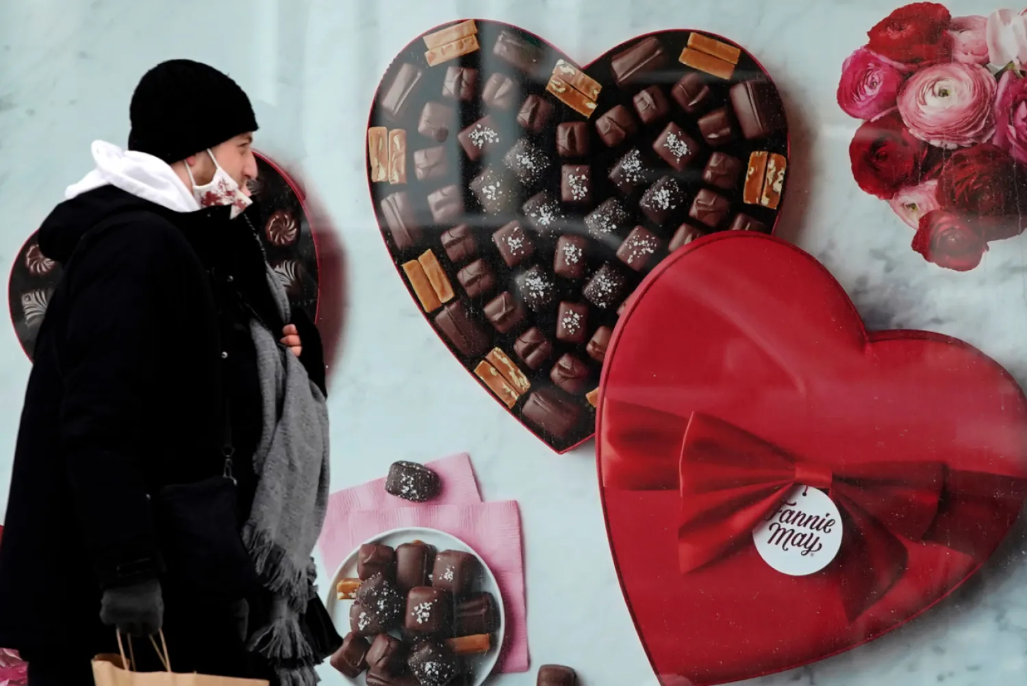 A man passes a Fannie May chocolate shop in downtown Chicago on Valentine's Day, Feb. 14, 2021. (AP Photo/Nam Y. Huh, File)