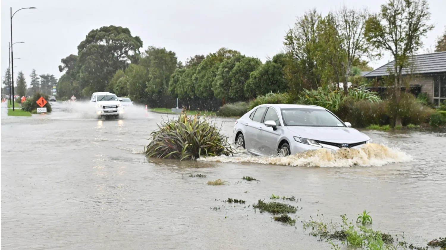 Vehicles drive through flood waters during a downpour in Lincoln at the Selwyn district in the Canterbury Region of New Zealand's South Island, May 1, 2025. (AFP)