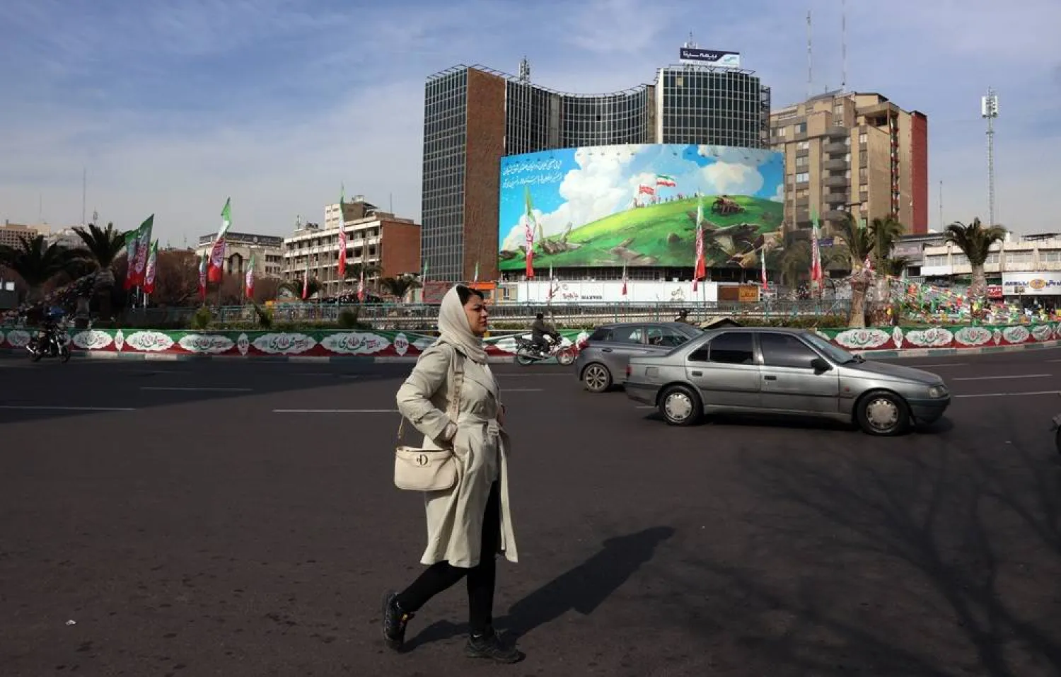An Iranian woman walks past an anti-US billboard at Valiasr Square in Tehran, Iran, 14 February 2026, amid heightened regional tensions following an increased US military presence in the Middle East. (EPA)