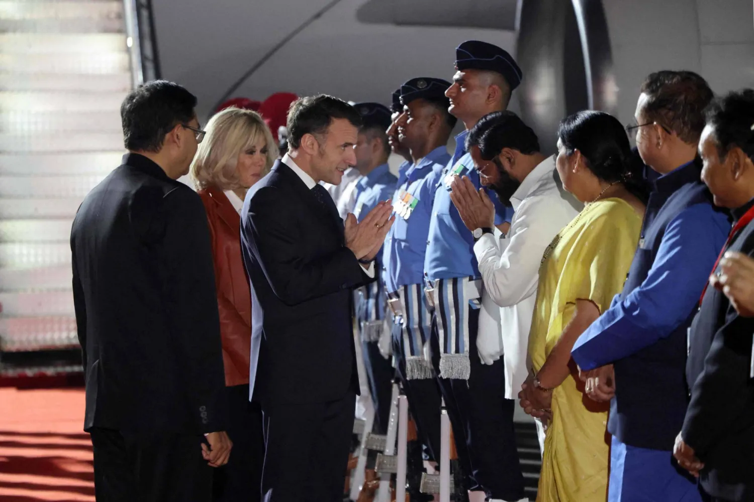 France's President Emmanuel Macron (C-R) and his wife Brigitte Macron (C) are welcomed by India's officials upon their arrival in Mumbai on February 17, 2026. (Photo by Ludovic MARIN / AFP)