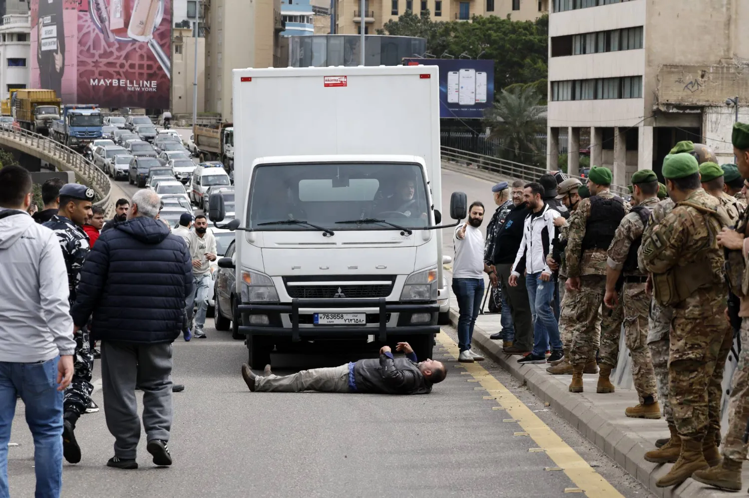 سائق سيارة أجرة يستلقي على الأرض أمام السيارات خلال تحرك احتجاجي على حزمة ضريبية جديدة أقرتها الحكومة اللبنانية (إ.ب.أ)