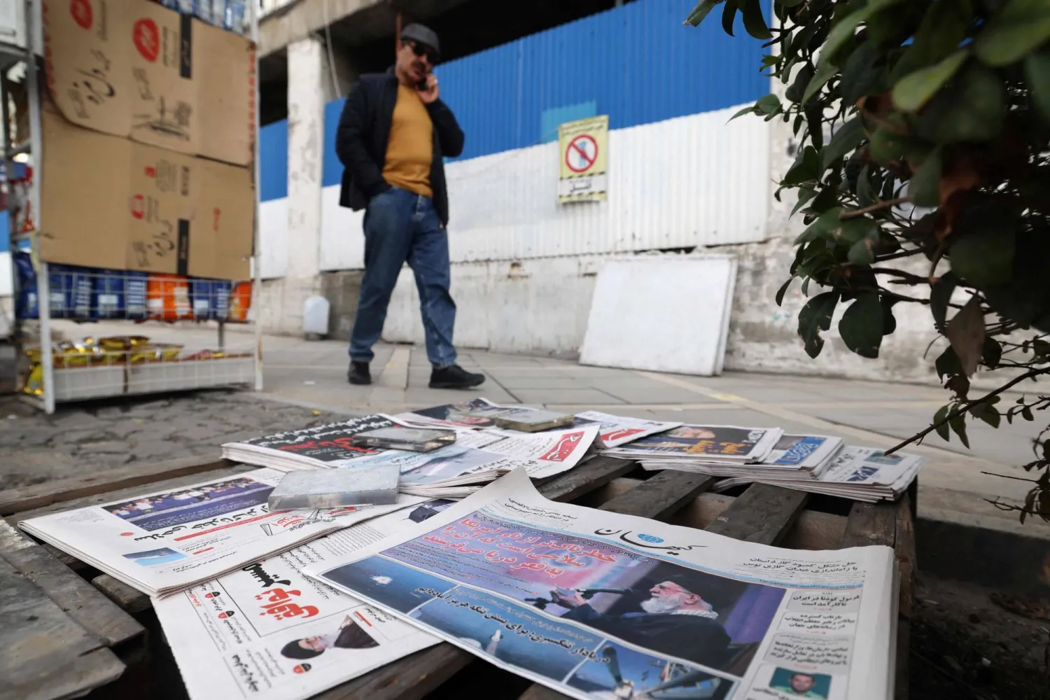 رجل يمر أمام كشك لبيع الصحف يعرض صورة المرشد علي خامنئي في طهران الأربعاء (أ.ف.ب)