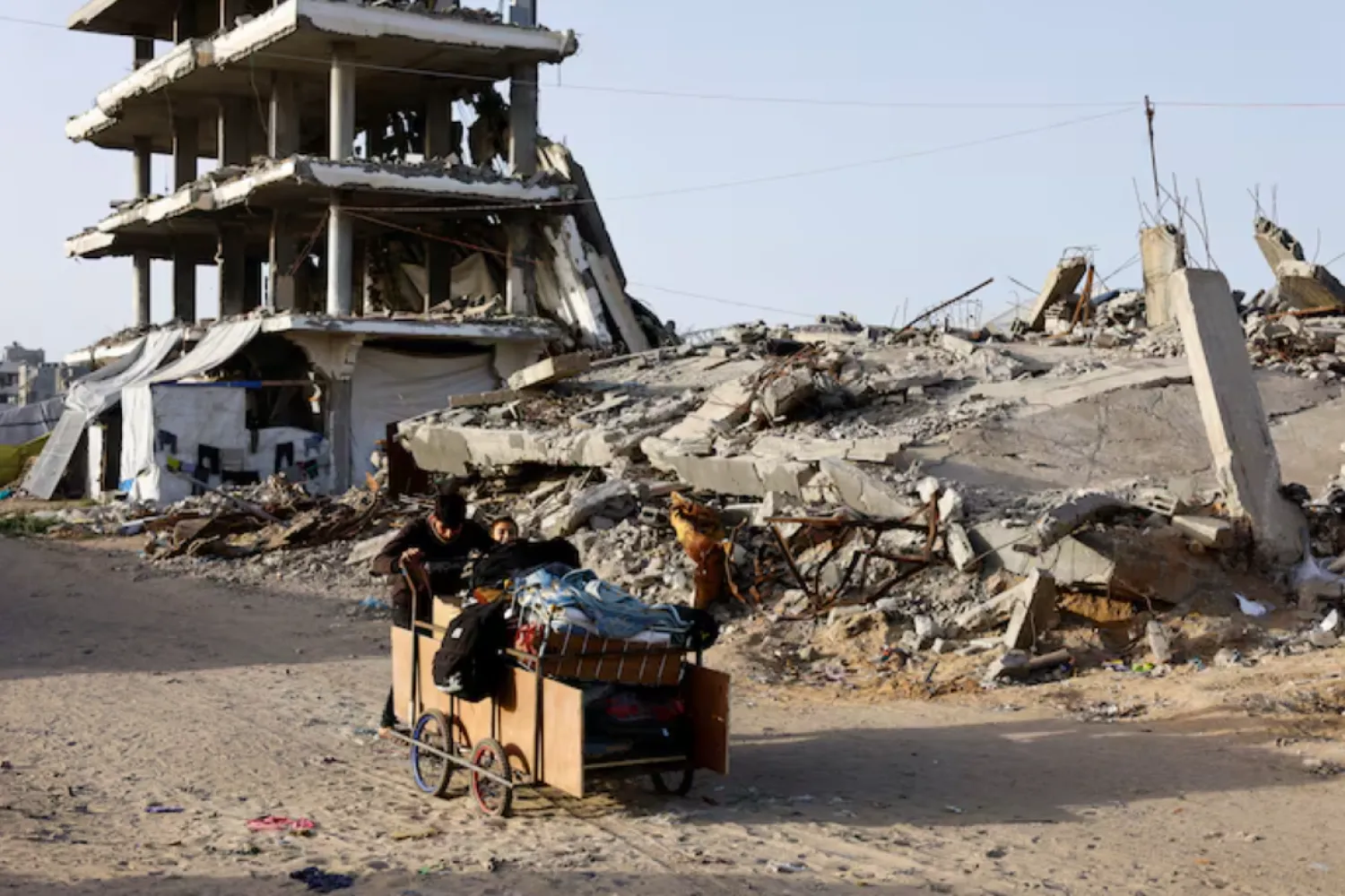 Palestinians push a cart past the rubble of residential buildings destroyed during the two-year Israeli offensives, in Gaza City, February 17, 2026. REUTERS/Mahmoud Issa
