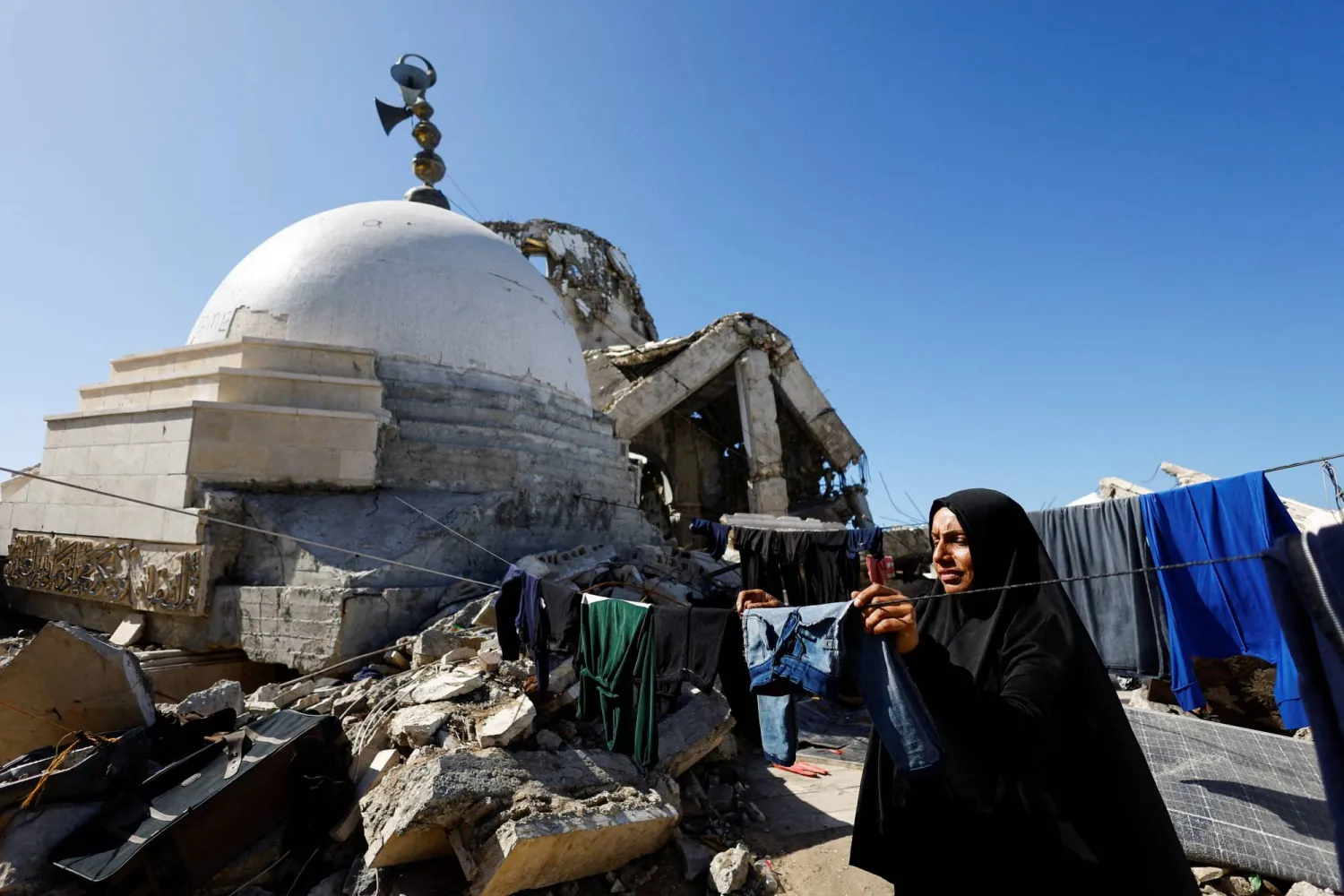 امرأة فلسطينية نازحة تعيش قرب مسجد دُمر خلال القصف الإسرائيلي على مدينة غزة (رويترز)