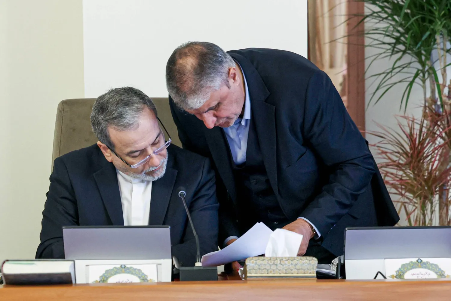 رئيس المنظمة الإيرانية للطاقة الذرية محمد إسلامي ووزير الخارجية عباس عراقجي يراجعان مسودة على هامش اجتماع الحكومة الأربعاء (الرئاسة الإيرانية)