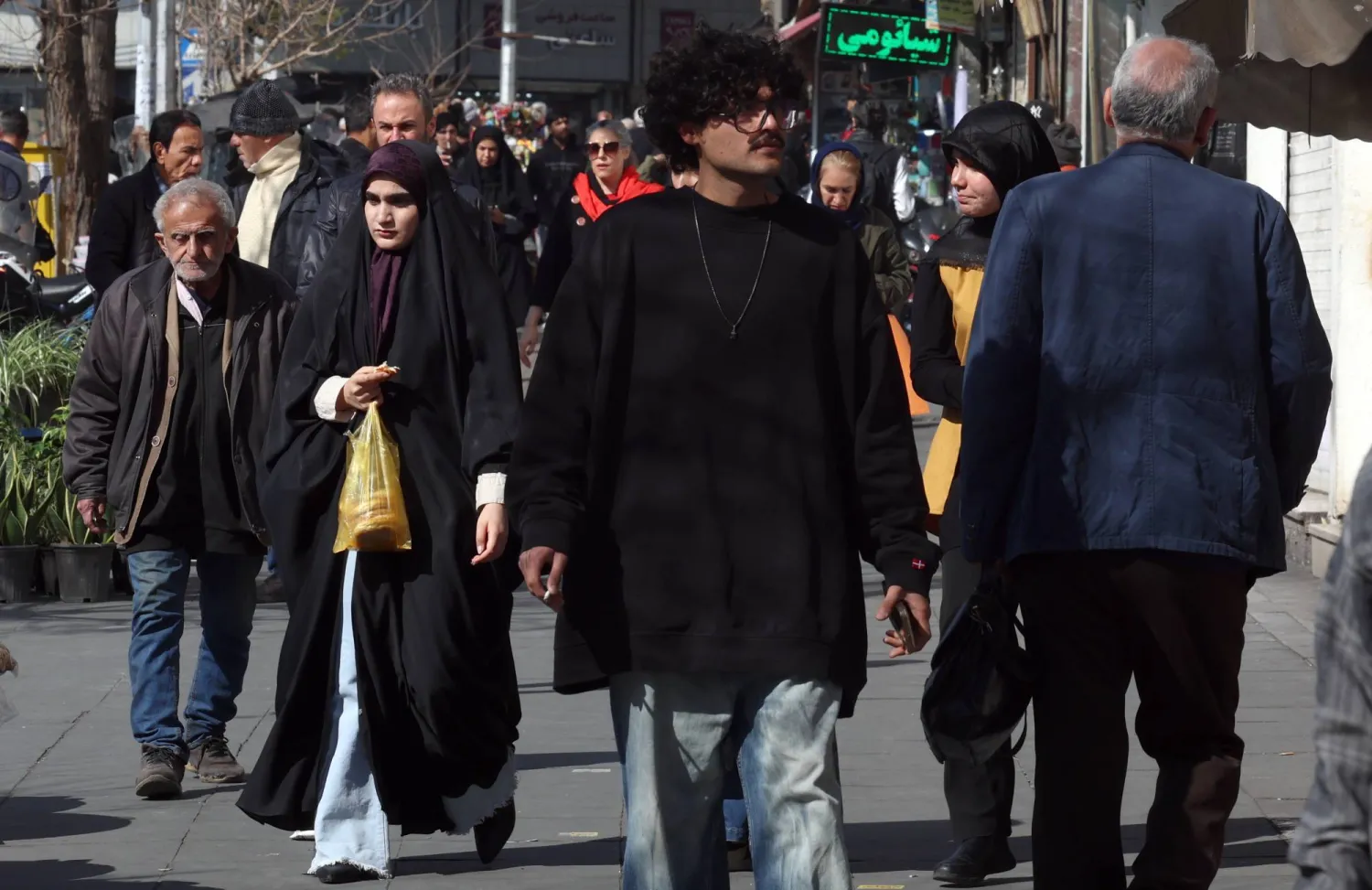 Iranians walk on a street in Tehran, Iran, 16 February 2026. (EPA)