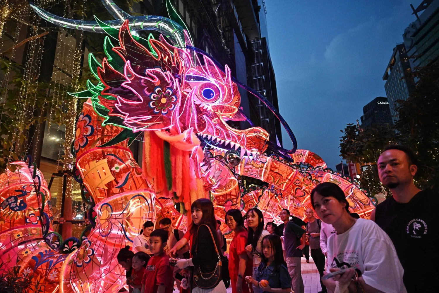 People gather to watch performers outside Emsphere shopping mall on the first day of the Lunar New Year of the Horse, in Bangkok on February 17, 2026. (Photo by Lillian SUWANRUMPHA / AFP)