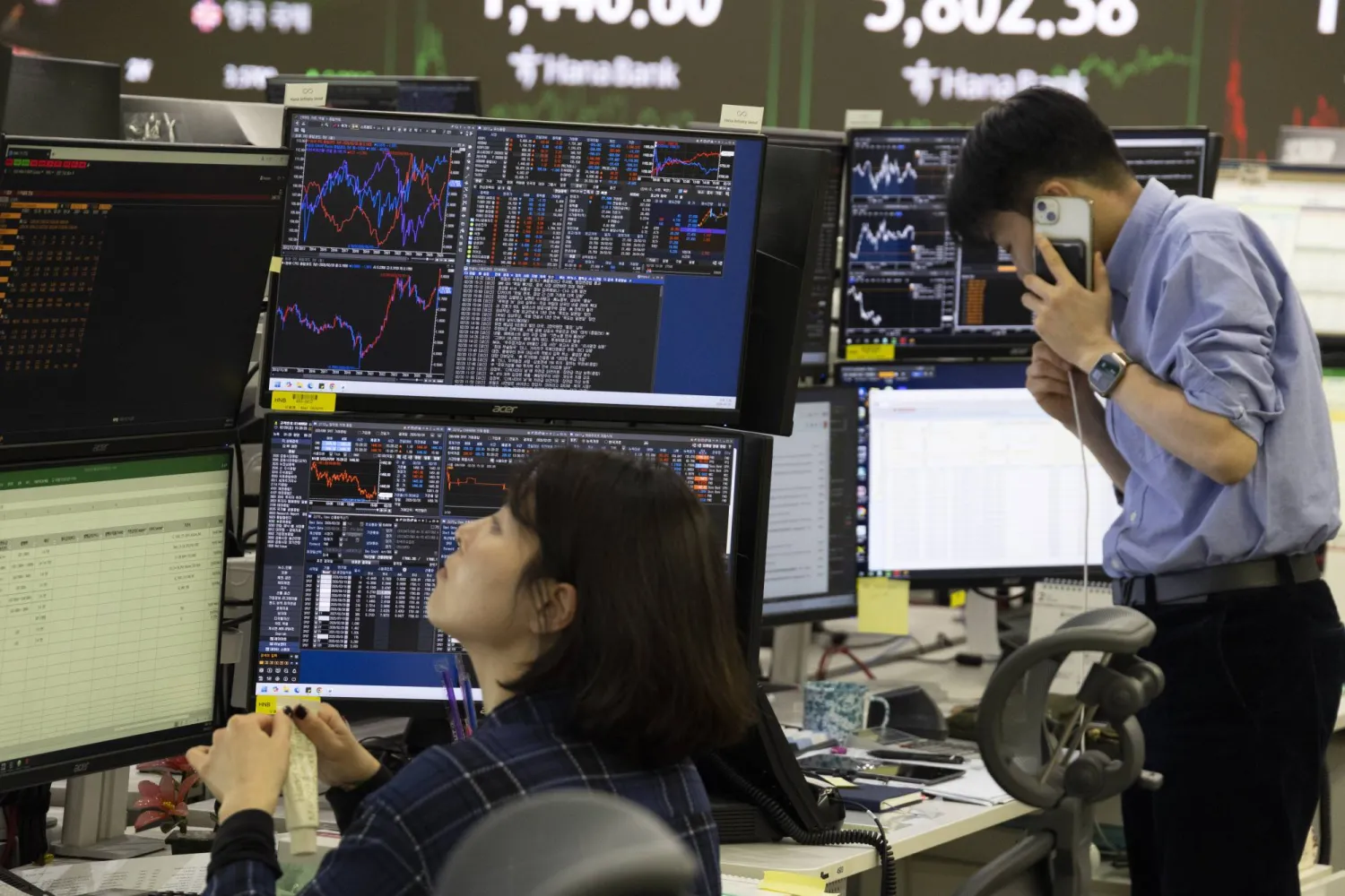 متعاملون كوريون جنوبيون يعملون أمام شاشات تعرض مؤشرات الأسهم في بنك هانا في سيول (إ.ب.أ)