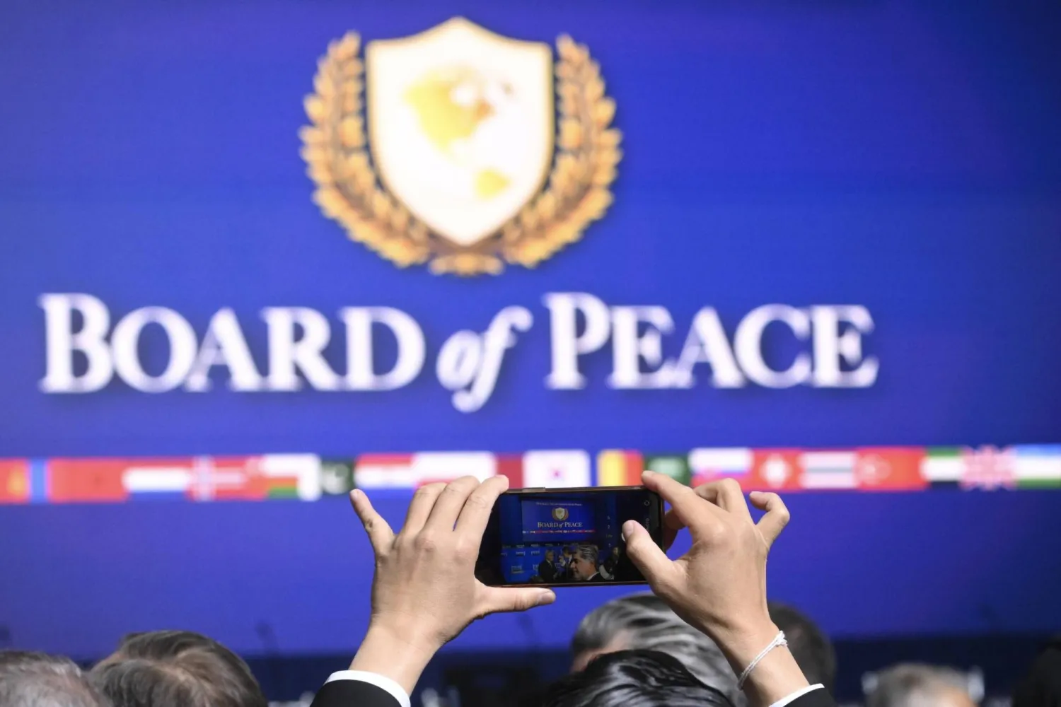 مشارك في اجتماع «مجلس السلام» لغزة يلتقط صورة للشعار خلال أول اجتماعاته في واشنطن الخميس (إ.ب.أ)