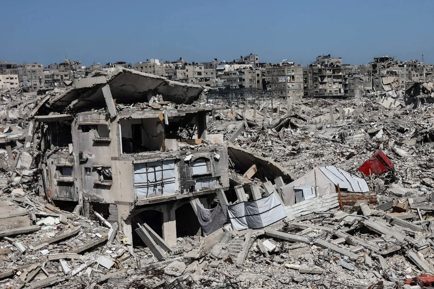 نُصبت خيامٌ تؤوي عائلات فلسطينية نازحة بين أنقاض المنازل والمتاجر التي دمرها الجيش الإسرائيلي في حي الشيخ رضوان بمدينة غزة (أ.ف.ب)