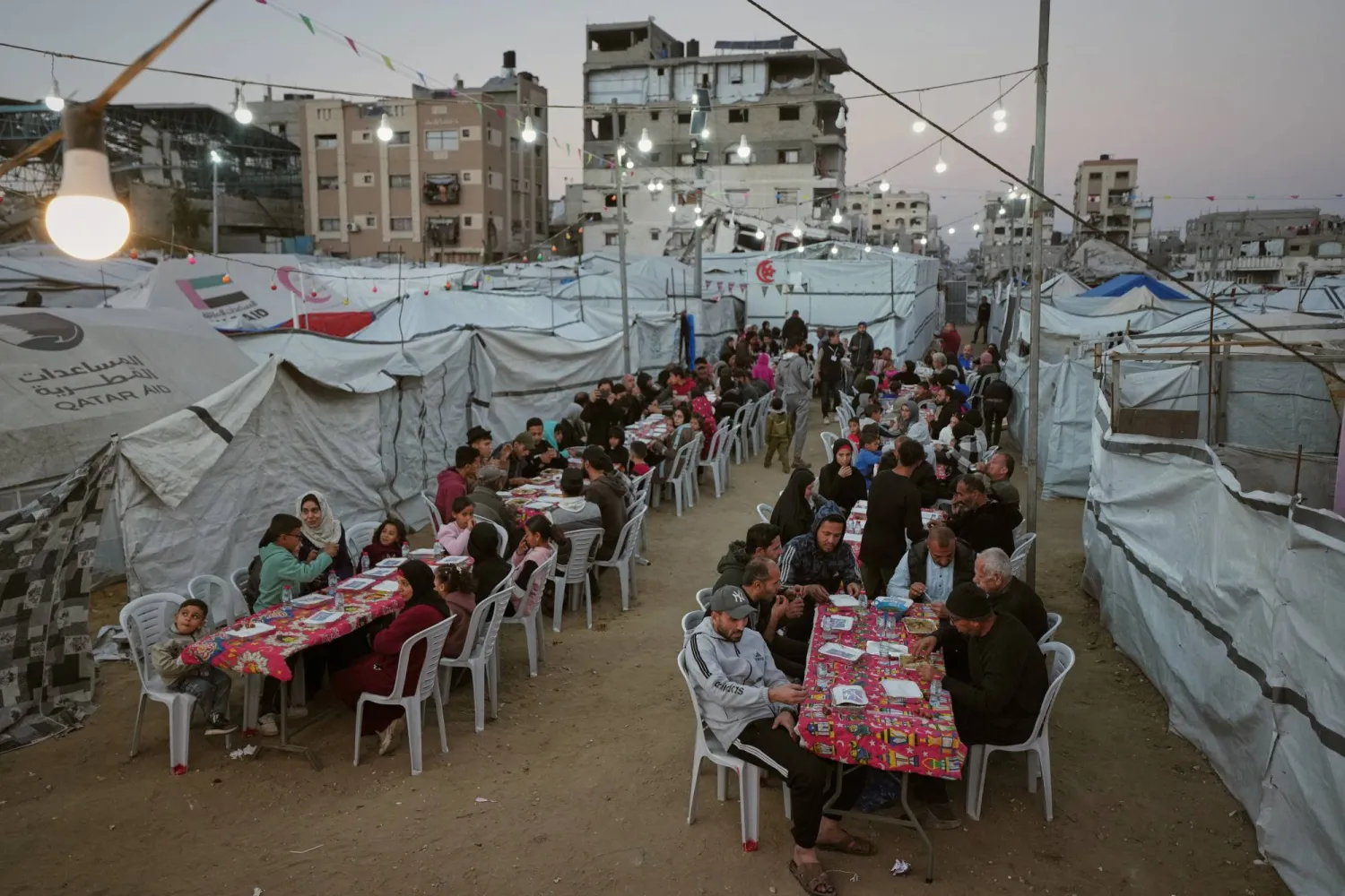 فلسطينيون يتجمعون لتناول الإفطار خارج خيامهم في معسكر للنازحين بمدينة غزة الجمعة (أ.ب)