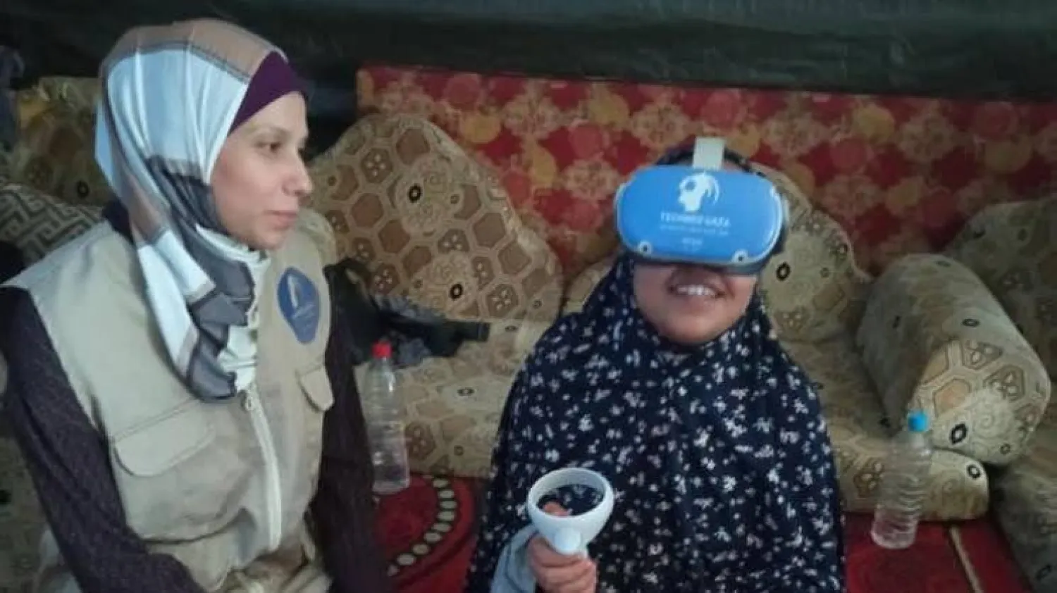 طفلة تتابع مشاهد افتراضية في غزة (يمين) مع إحدى العاملات في مشروع «تك ميد غزة» (صفحة المشروع على «إنستغرام»)