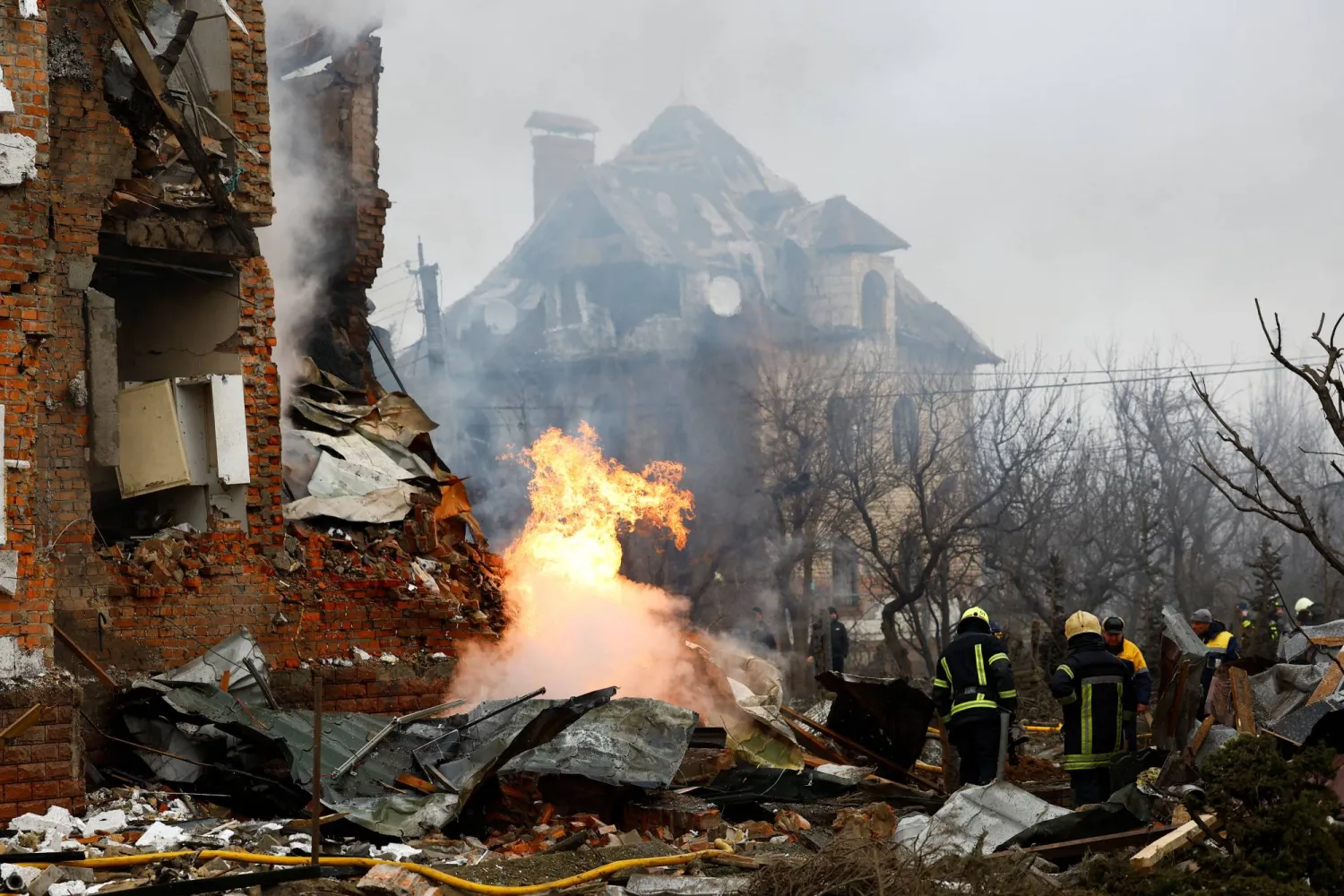 رجال إطفاء أوكرانيون أمام مبنى سكني تضرر جراء الغارات الروسية على كييف (رويترز)