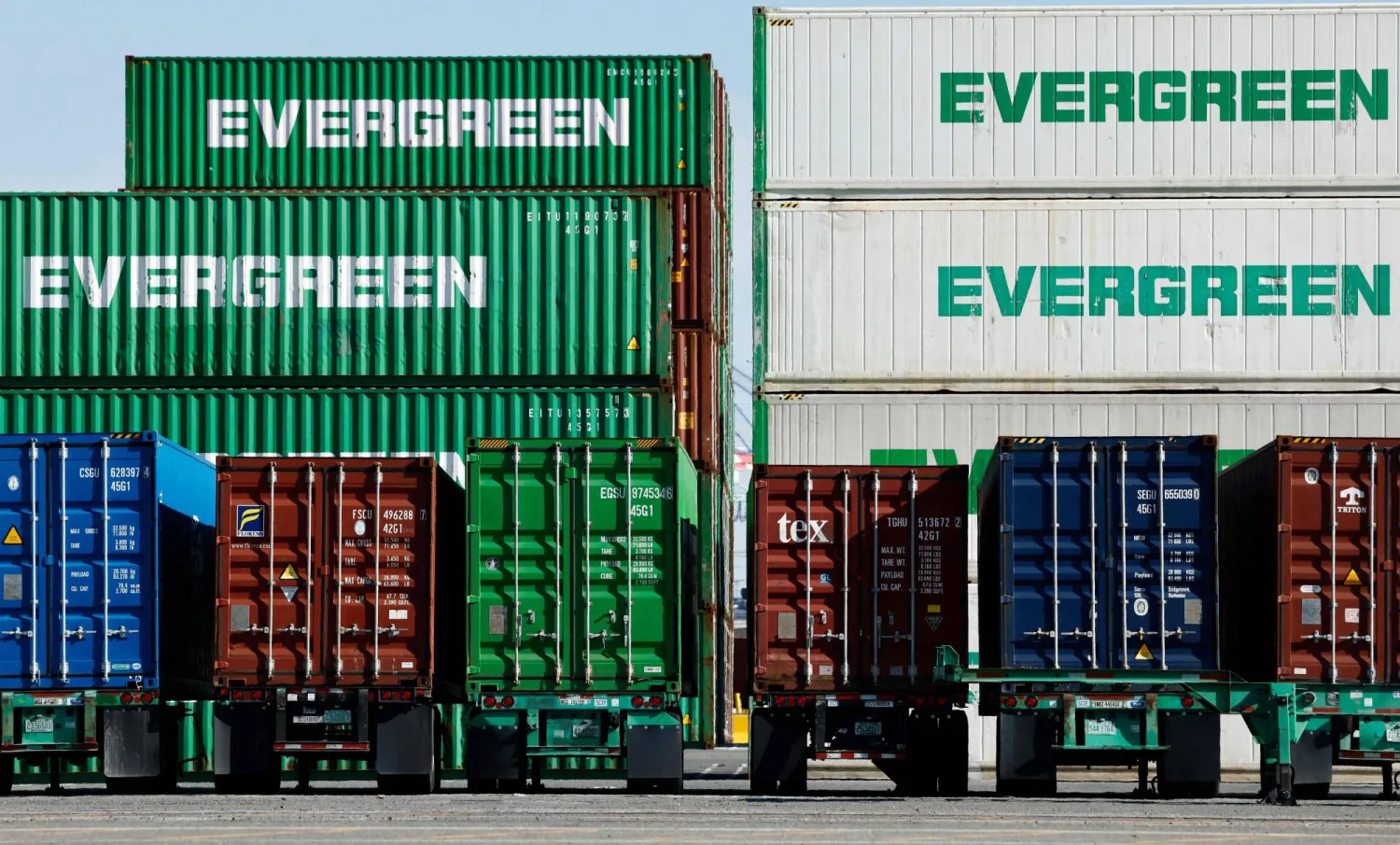 حاويات شحن مكدسة بينما تستقر أخرى على هياكل شاحنات نقل في ميناء لوس أنجليس (أ.ف.ب)