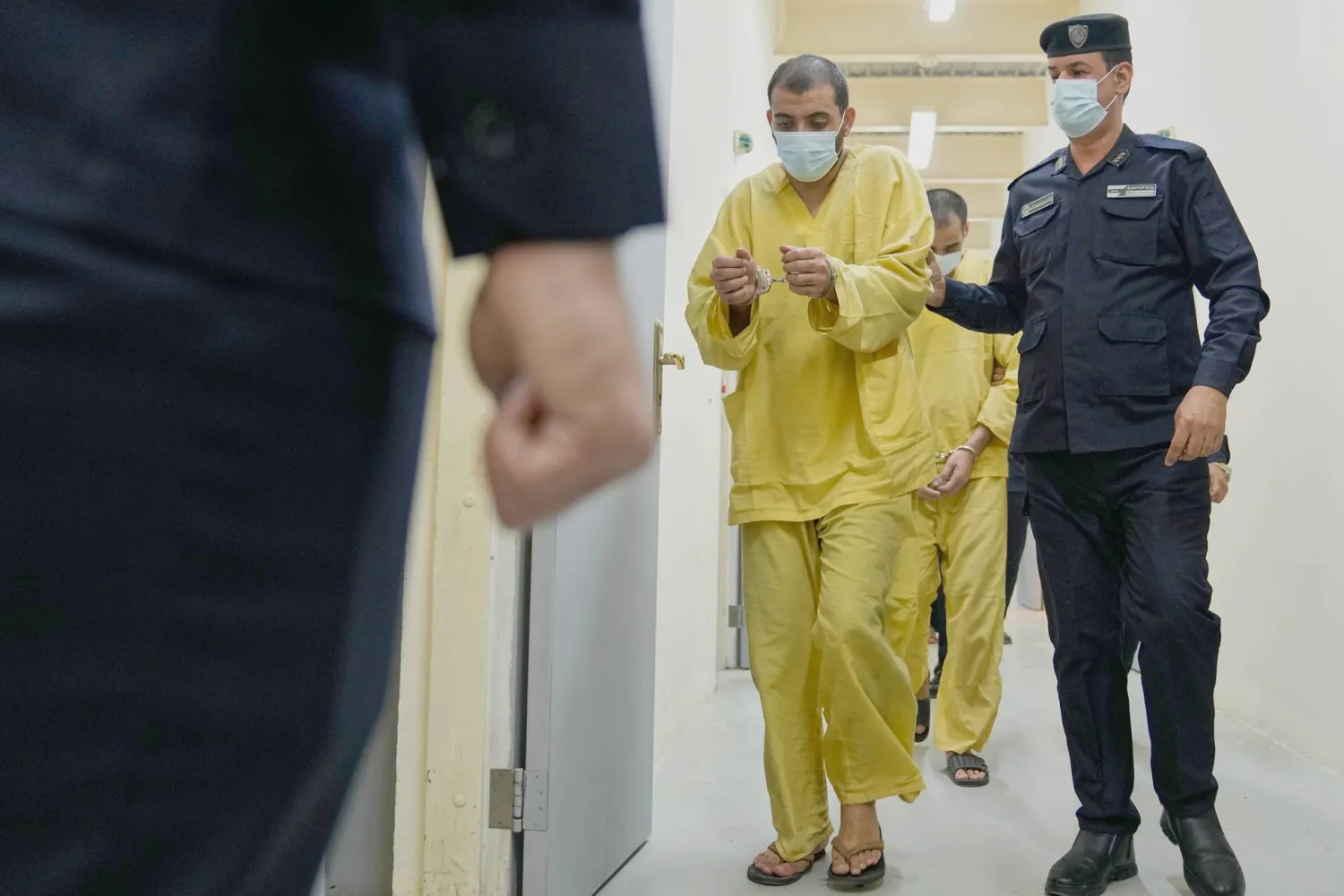 رجل أمن عراقي مع عناصر من «داعش» في «سجن الكرخ» ببغداد (أ.ب)