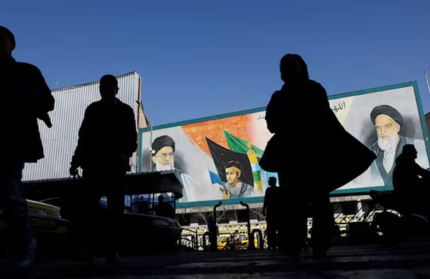 People walk near a mural featuring images of Iran's Supreme Leader Ayatollah Ali Khamenei and leader of Iran's 1979 Islamic Revolution Ayatollah Ruhollah Khomeini, on a street in Tehran, Iran, February 17, 2026. Majid Asgaripour/WANA (West Asia News Agency) via REUTERS 