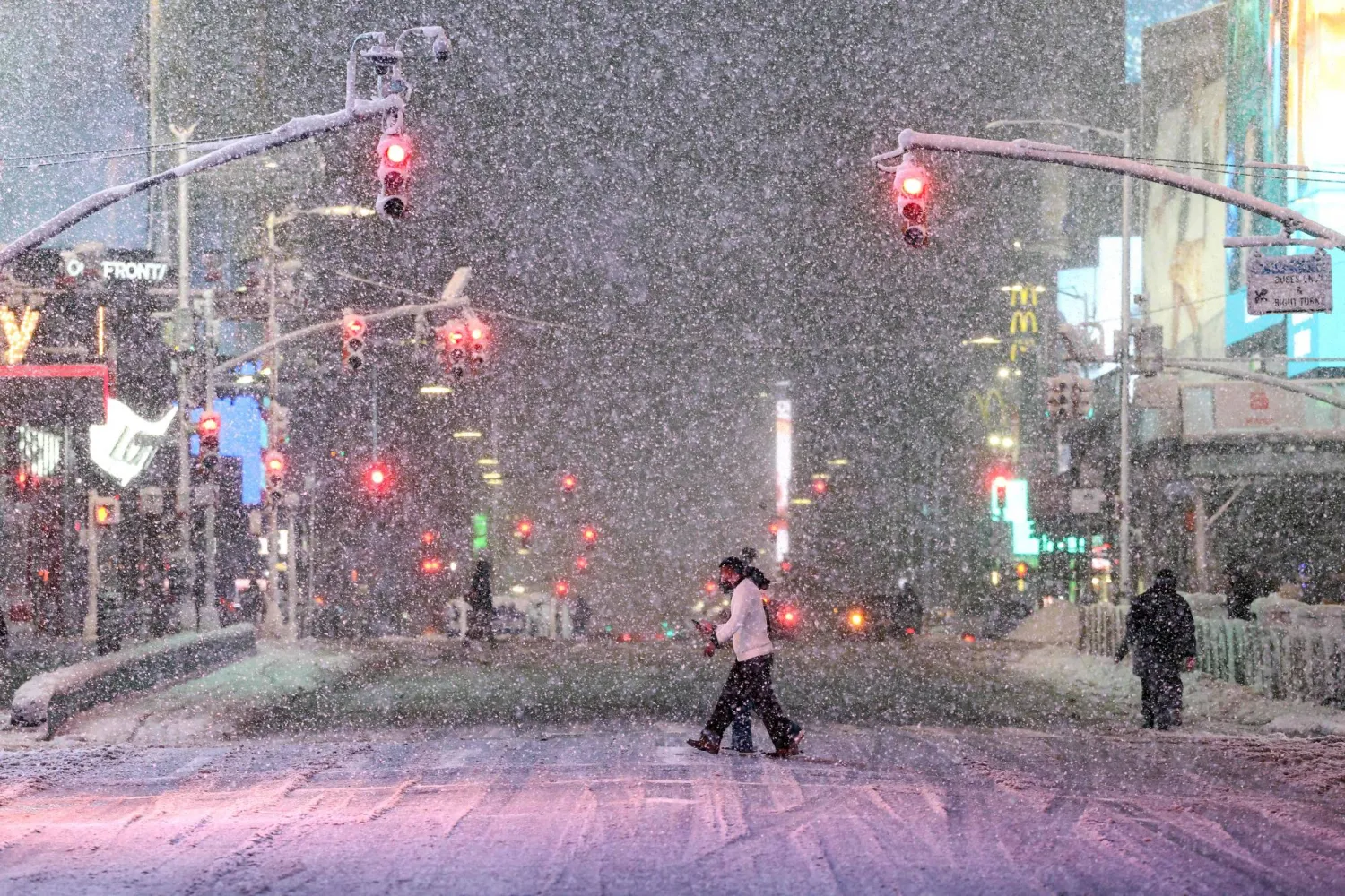 People walk along Manhattan's Times Square during a snowfall in New York City, on February 22, 2026. (AFP)