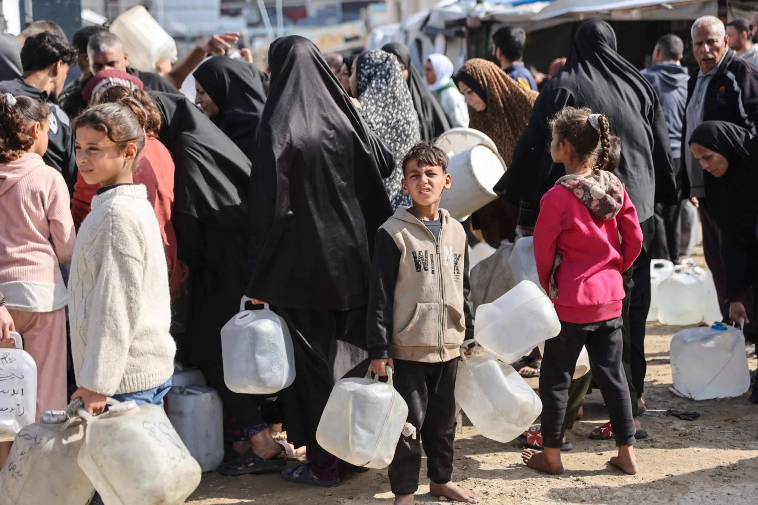 نازحون فلسطينيون ينتظرون ملء المياه في مخيم الرمال بمدينة غزة أول من أمس (أ.ف.ب)