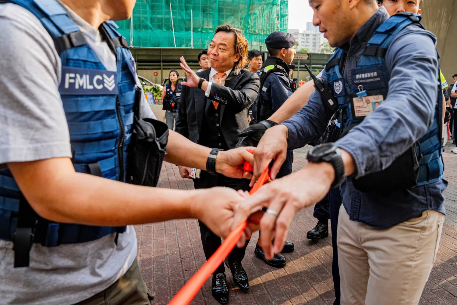 وصل المتهم لورنس لاو واي تشونغ (الوسط) من بين الـ12 ناشطاً مؤيّداً للديمقراطية إلى محكمة غرب كولون الجزئية بهونغ كونغ بالصين (أ.ف.ب)