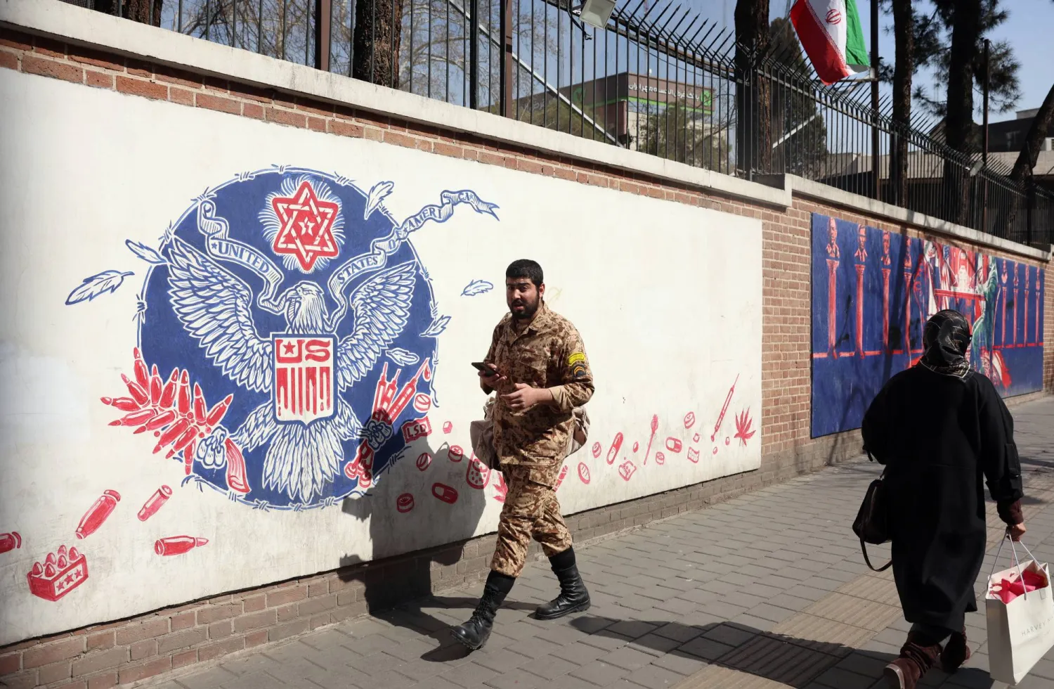 جندي إيراني يمر بجوار جدارية مناهضة للولايات المتحدة في طهران (إ.ب.ا) 