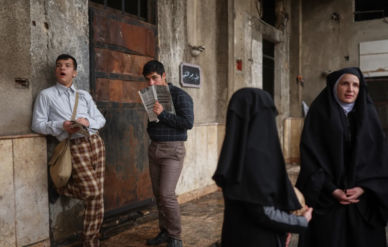 Extras stand by as a television crew films an episode of the TV series “Al-Souriyoun al-Aada” (“The Syrian Enemies”), based on a novel of the same name that was banned under Bashar Assad, along a transformed street in central Aleppo, Syria, Friday, Feb. 13, 2026. (AP Photo/Ghaith Alsayed)

